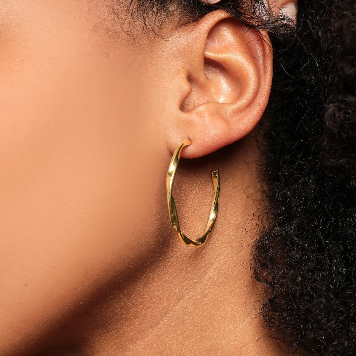 Close up of woman wearing AEC Paris Moana Gold Hoop earrings on white background