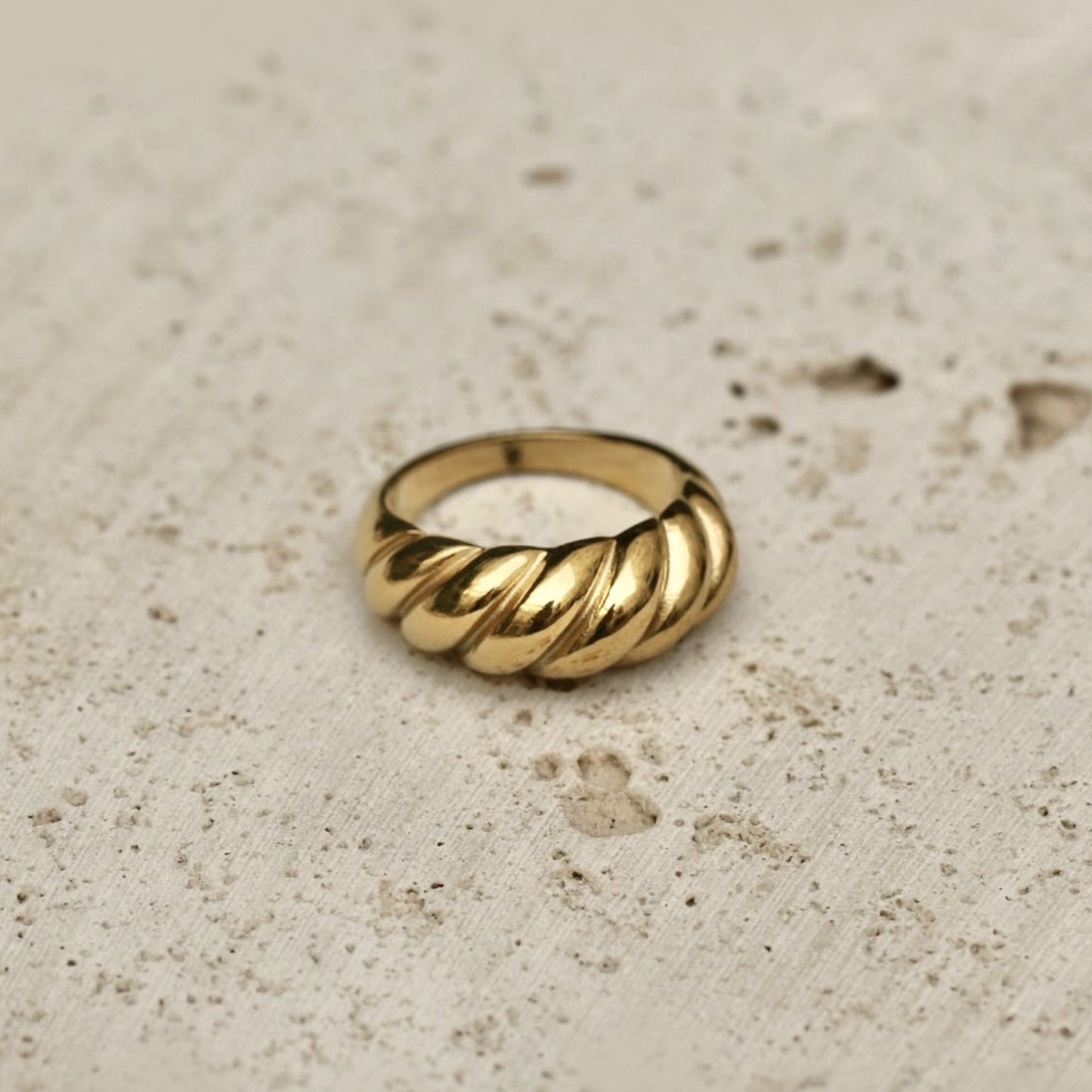Shown on a surface, the size 8 AEC Paris Aquarius Gold ring - solid croissant ring in 18k gold-plated stainless steel, durable, hypoallergenic, minimalist design, luxury everyday jewellery.