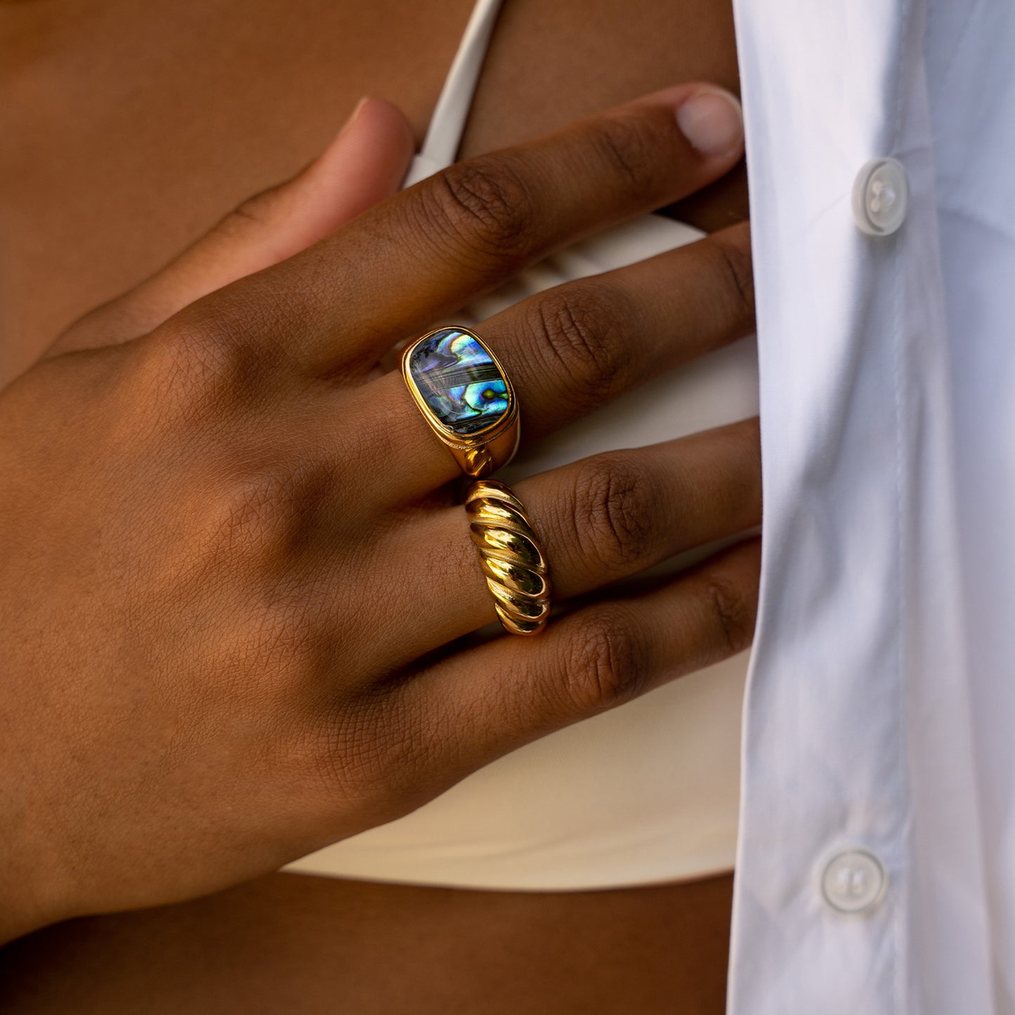 Close up on a womans hand her rings with the size 6 AEC Paris Aquarius Gold ring - solid croissant ring in 18k gold-plated stainless steel, durable, hypoallergenic, minimalist design, luxury everyday jewellery.