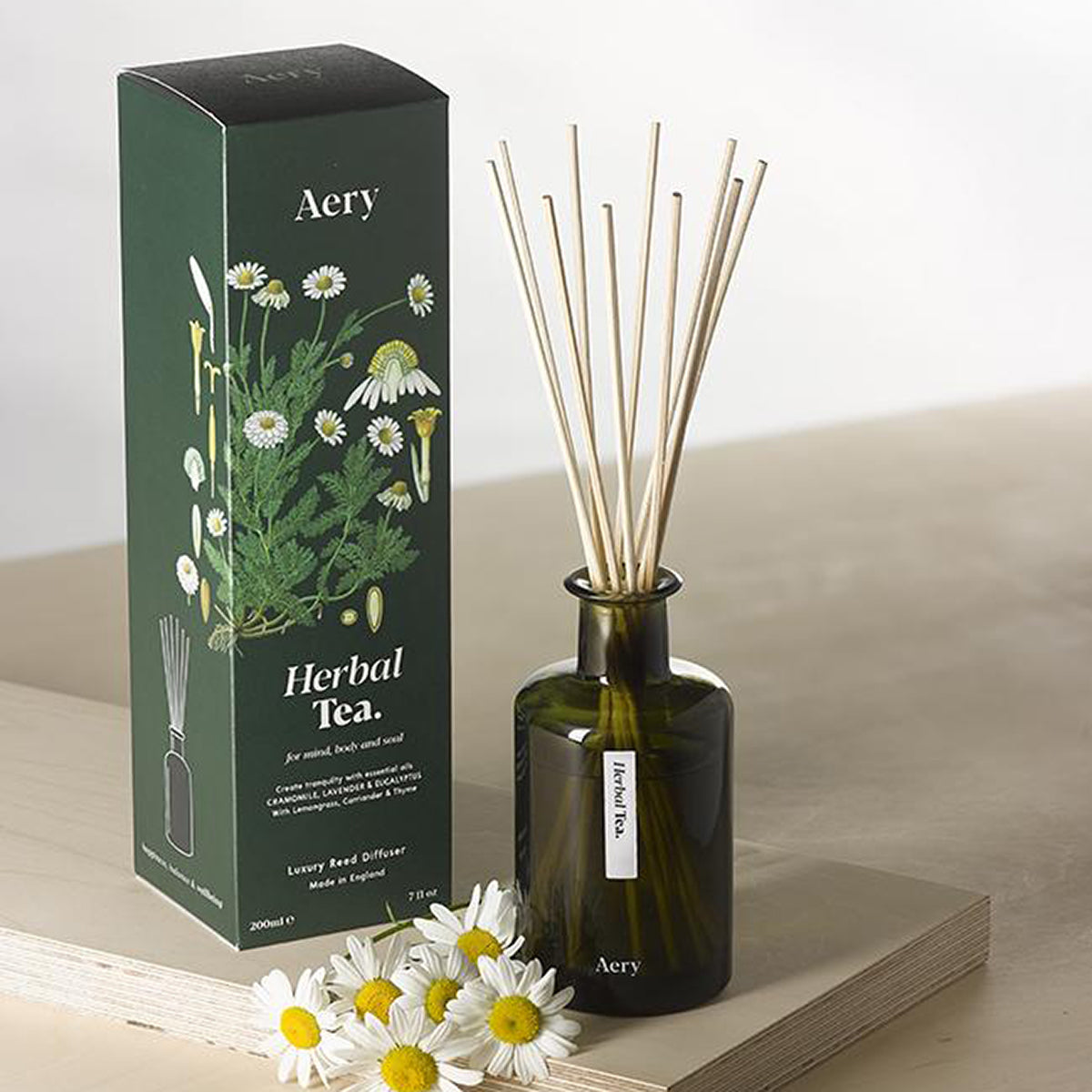 Aery Herbal Tea 200ml diffuser from the Botanical Green collection showing diffuser and packaging on wood with daisies