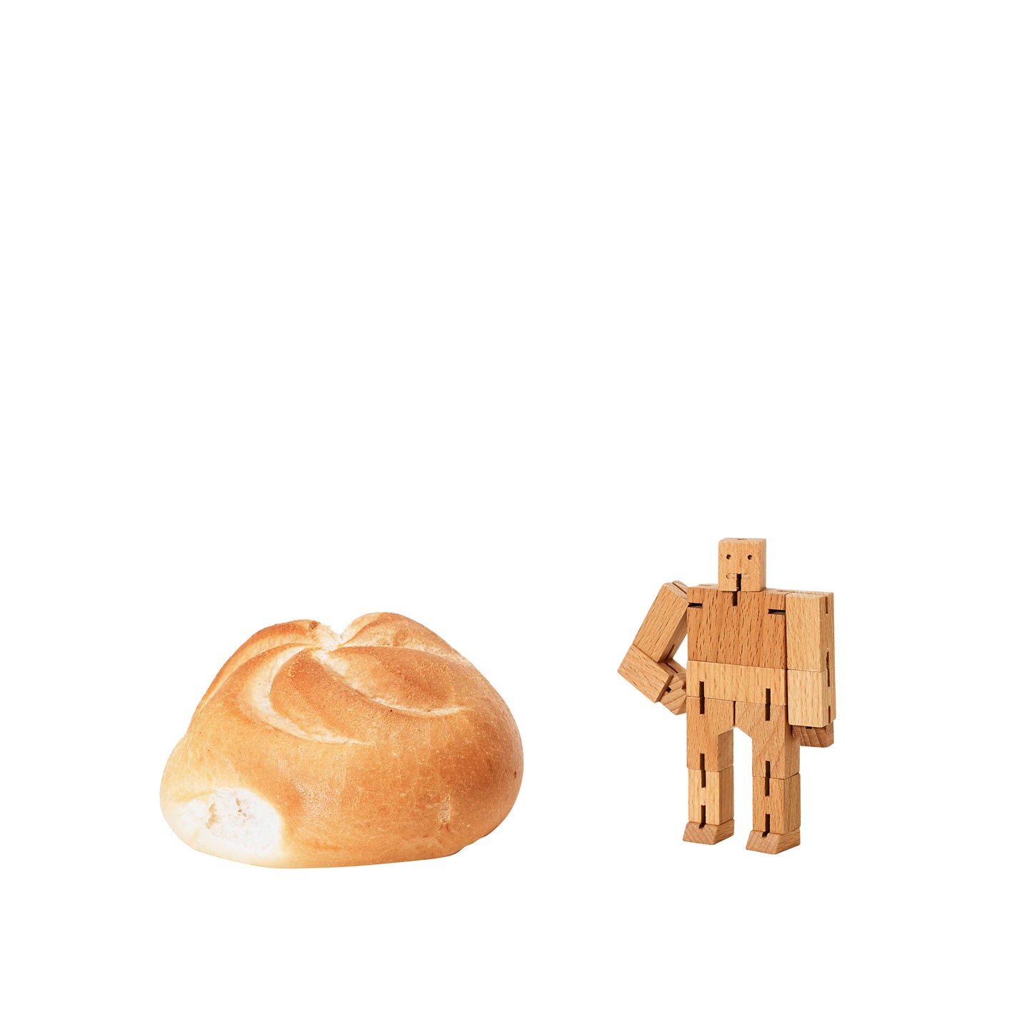 Shown with a circle bread Areaware Cubebot Micro wooden toy robot - natural beech-wood figure with elastic joints, folds into a 1.5-inch cube and poses in multiple positions; compact, durable, and suitable for ages 4+.