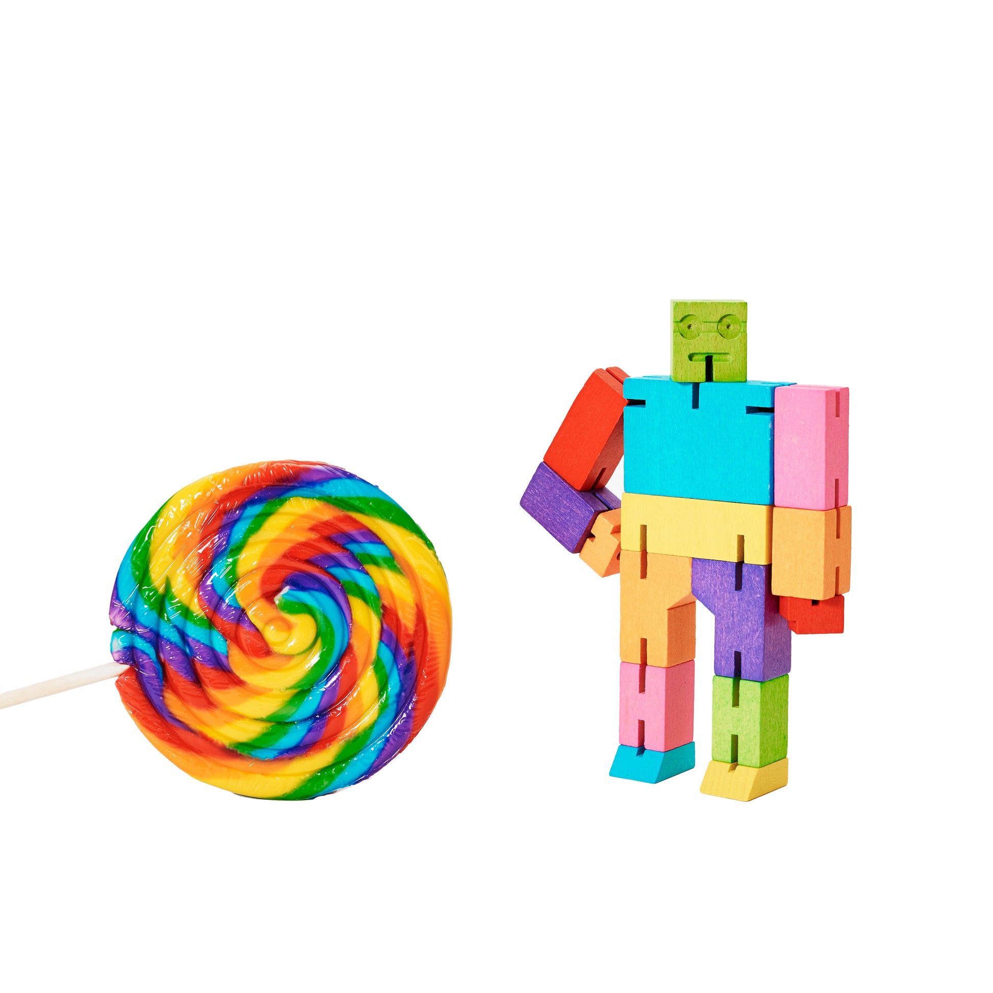 Shown with a multicolored candy on a stick Areaware Cubebot Small Multi wooden toy robot - multicolor beech-wood figure with elastic joints and water-based paint, folds into a 1.5-inch cube and poses in multiple positions; compact, durable, and suitable for ages 4+.