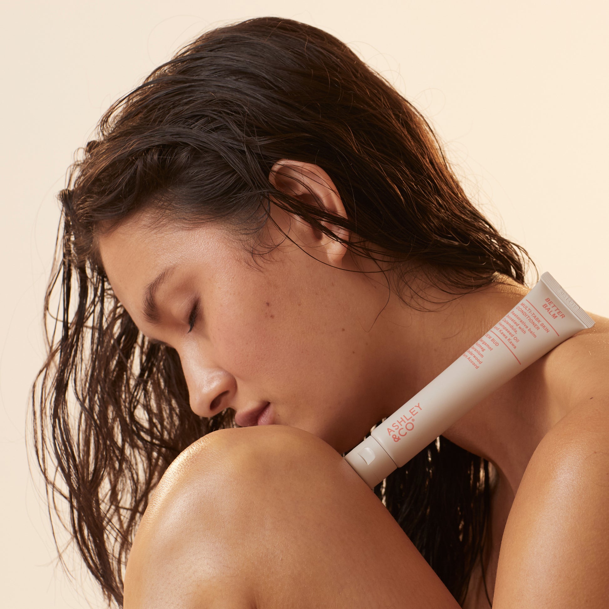 Ashley and Co 'Better Balm' skin conditioner in dew bud fragrance resting on a woman's knee and shoulder.