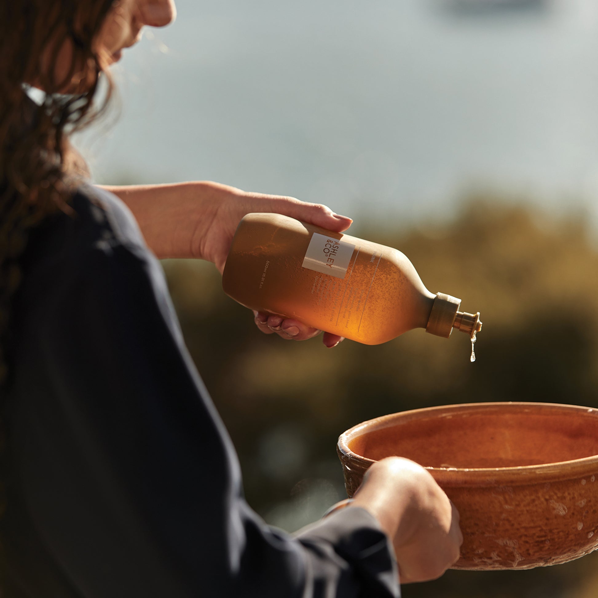 Ashley and Co 'Insink' dish wash in lotus leaf & lustre fragrance squeezing detergent into a pot.