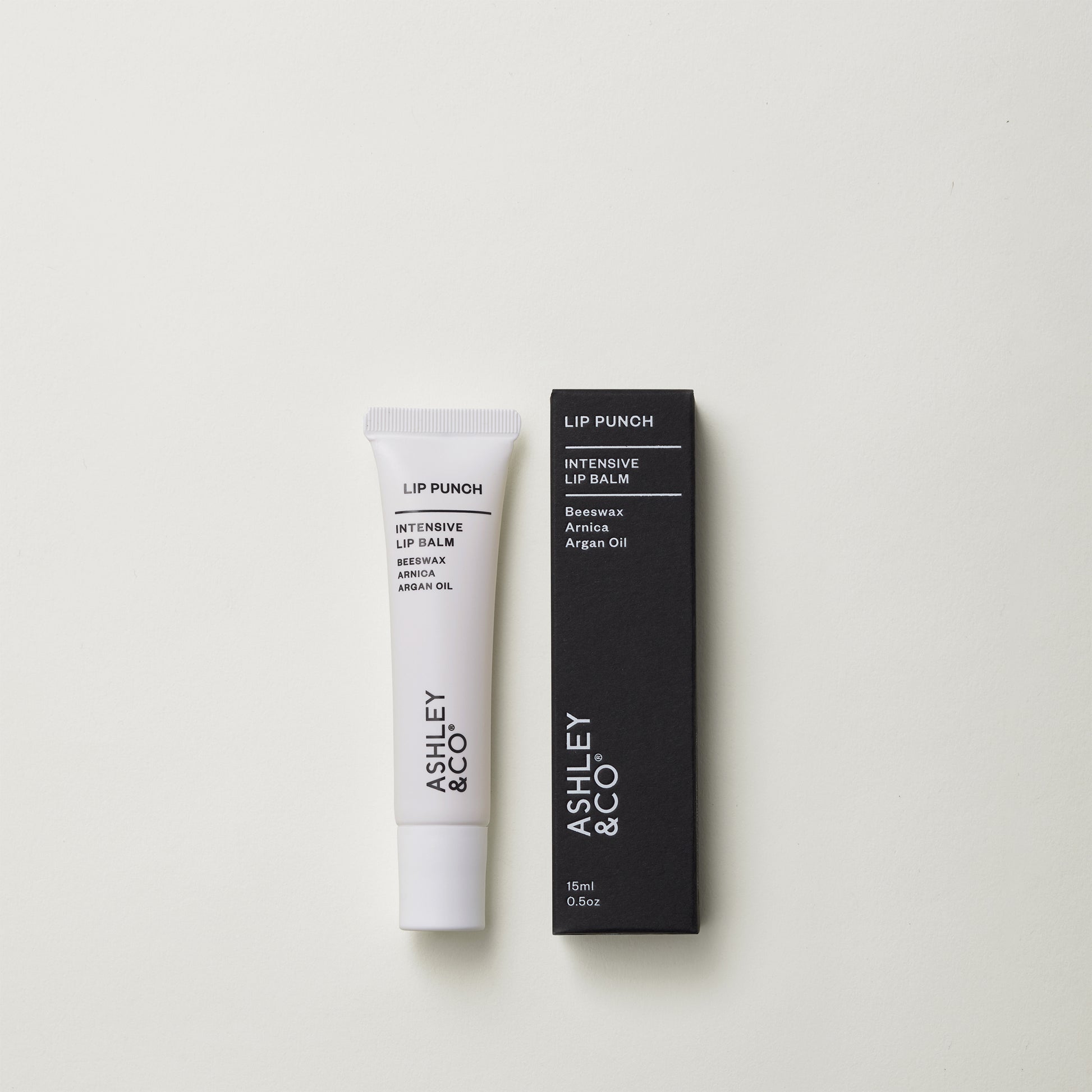 Ashley and Co 'Lip Punch' intensive lip balm on a grey background.
