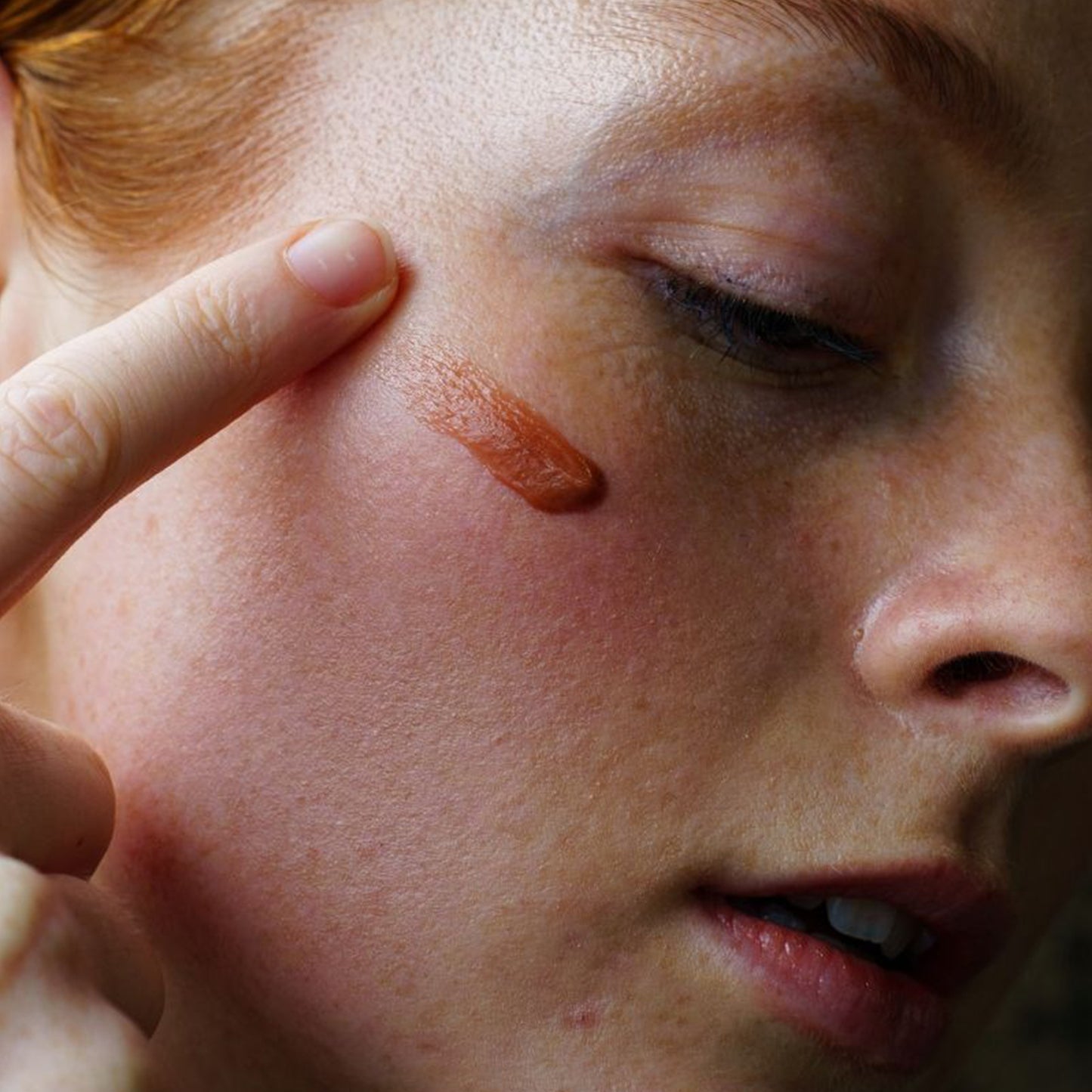 Ashley and Co 'Tint Me Lip Punch' coffee date coloured lip balm smudged onto a woman's cheek.
