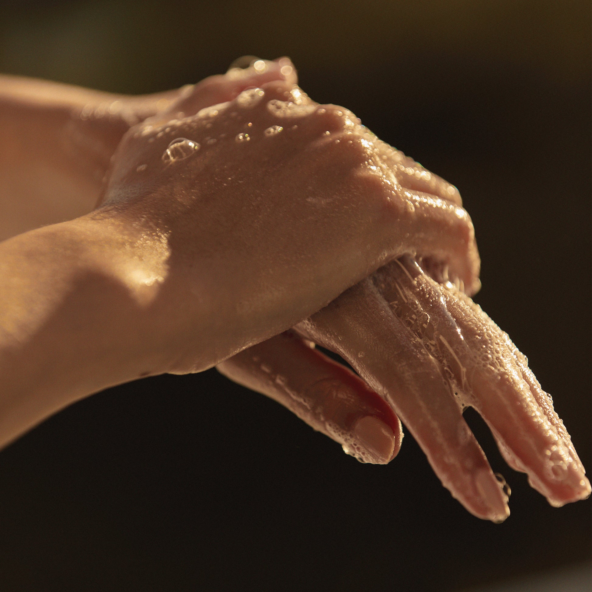 A person washing their hands using Ashley and Co 'Mini Bar' body soap in tui and kahili fragrance.