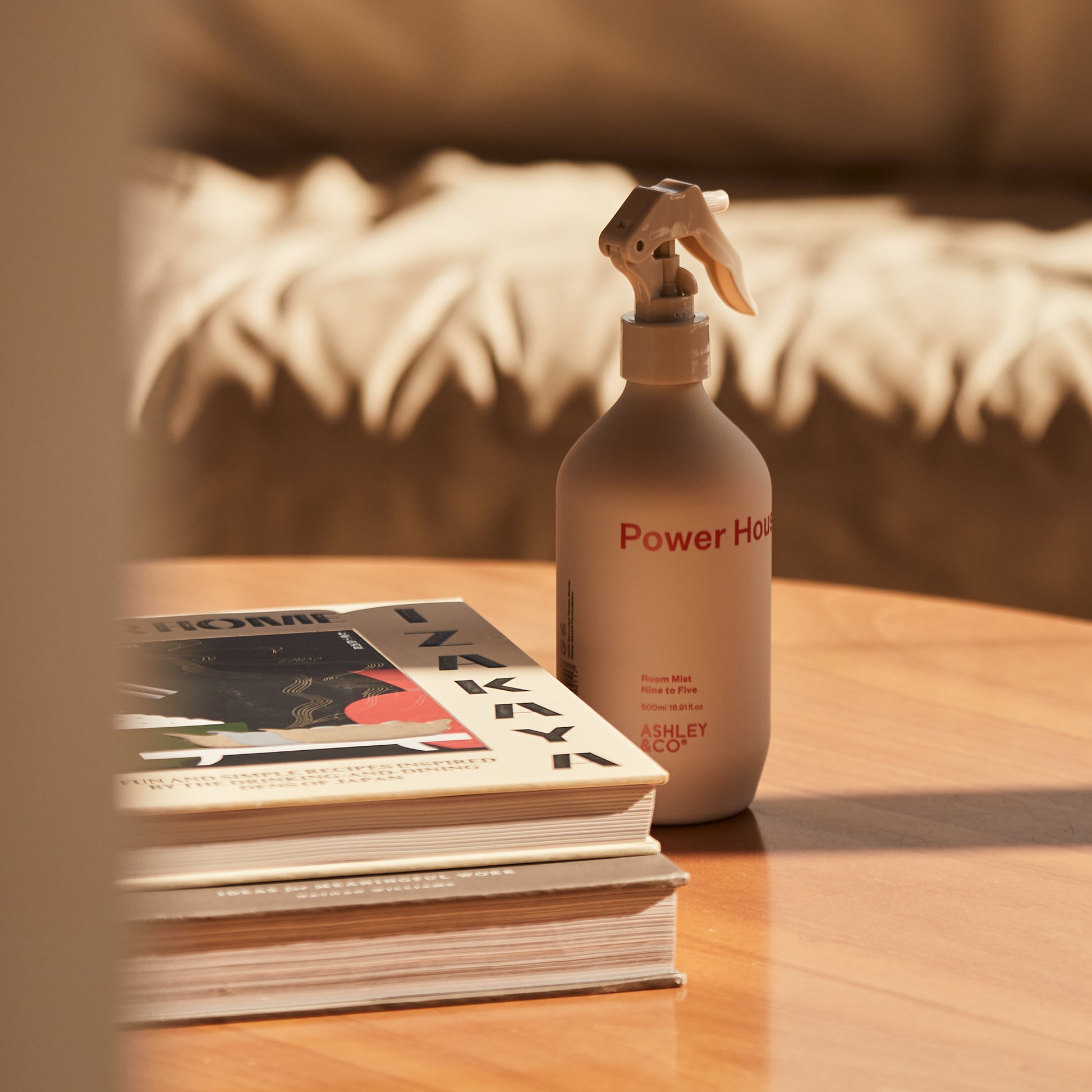 A bottle of Ashley and Co 'Power House' room mist in nine to five fragrance placed on a coffee table.