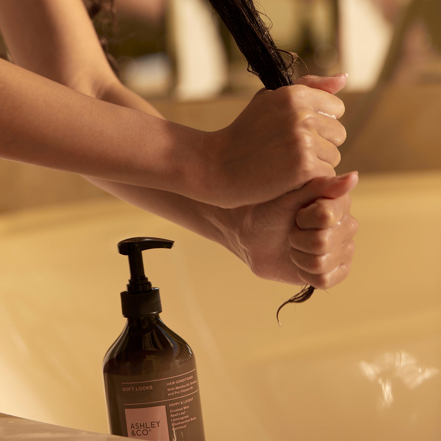 Woman conditioning her hair using Ashley and Co "Soft Locks' hair conditioner in Peppy and Lucent scent.