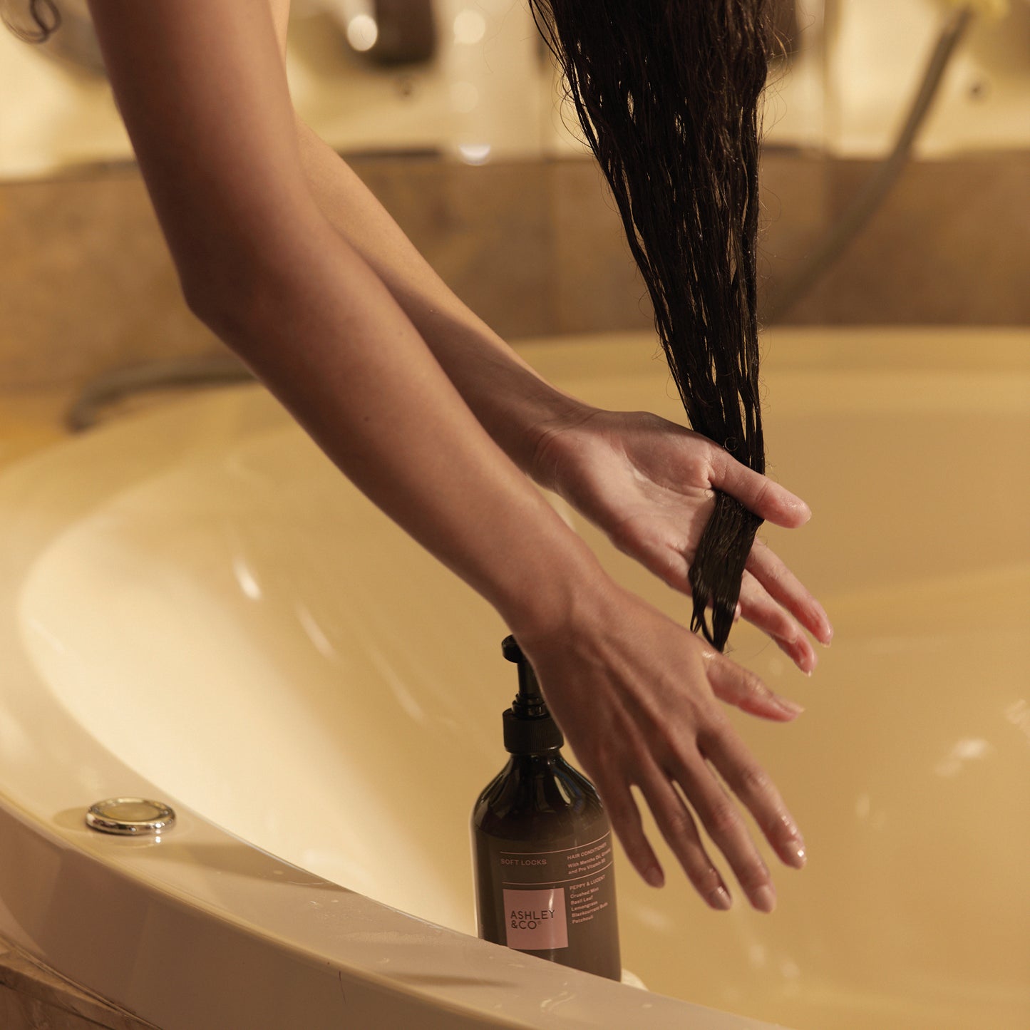 Woman conditioning her hair using Ashley and Co "Soft Locks' hair conditioner in Peppy and Lucent scent.