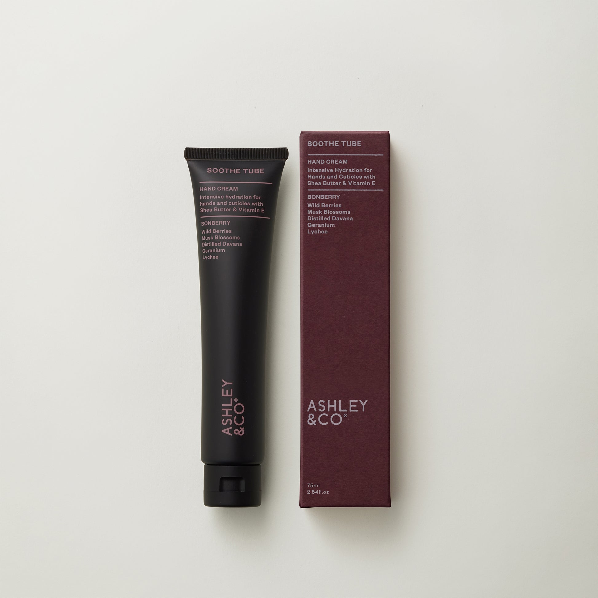 Ashley and Co 'Soothe Tube' handcream in bonberry fragrance on a grey background.