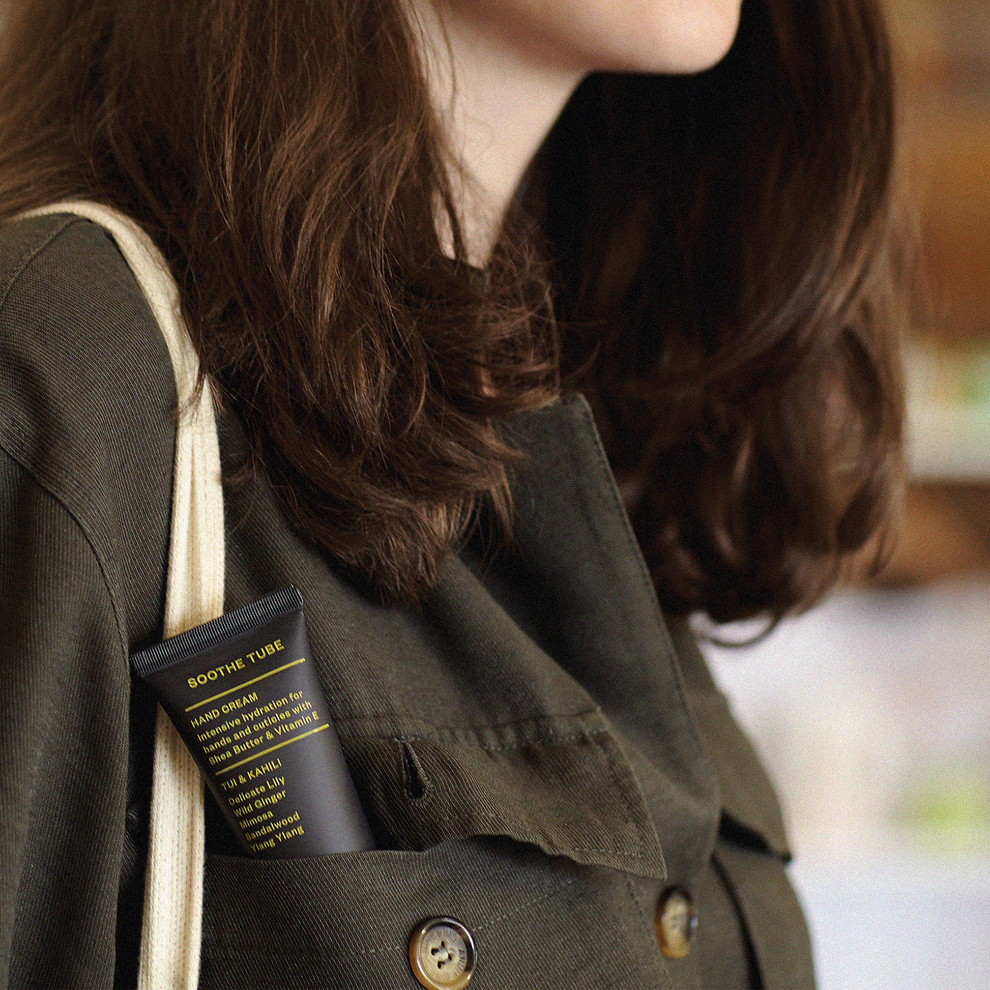 Ashley and Co 'Soothe Tube' handcream in tui and kahili fragrance poking out of the pocket on a womans shirt.
