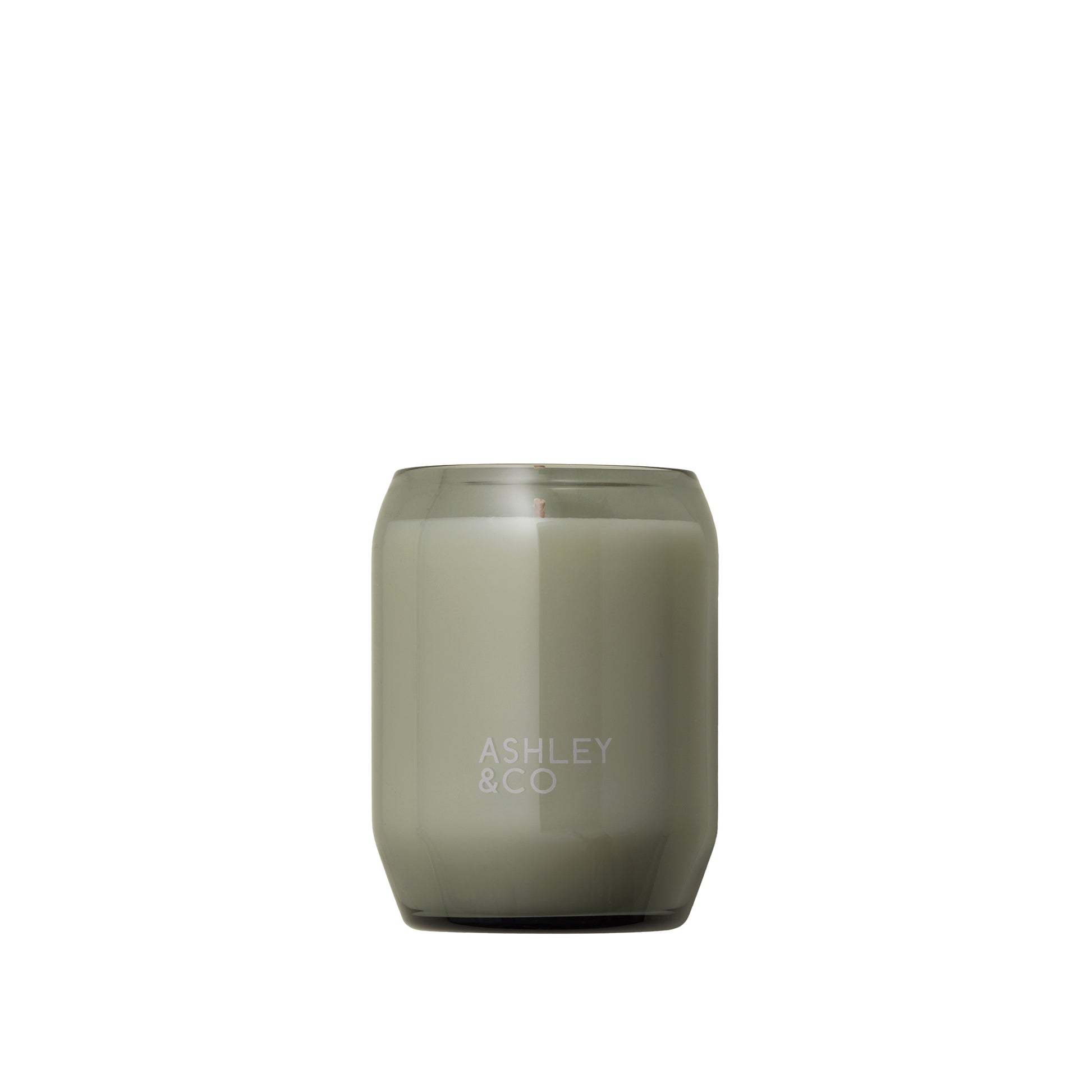 Woman sitting next to an Ashley and Co 'Waxed Perfume' scented candle in bonberry fragrance.