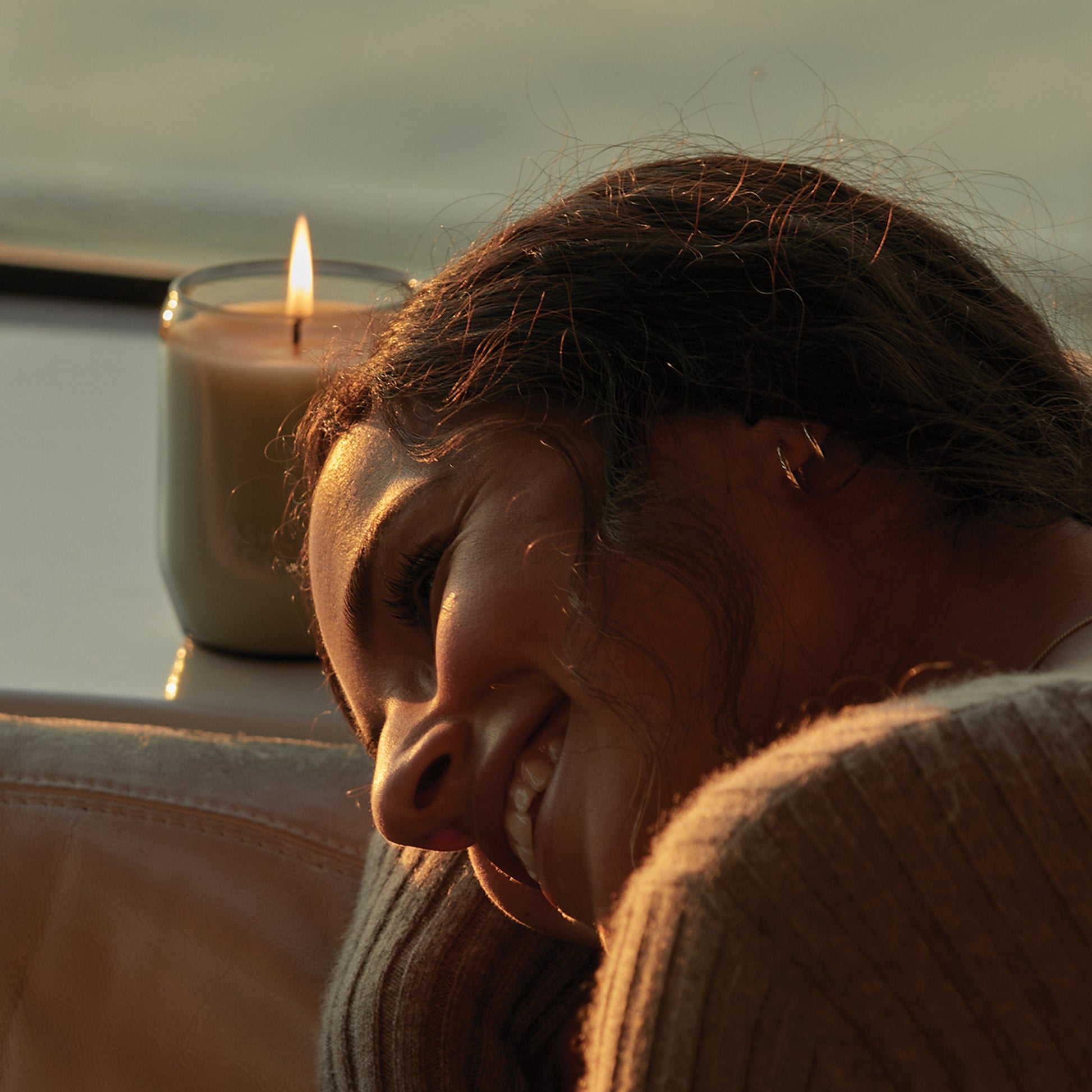 Ashley and Co 'Waxed Perfume' scented candle in tui and kahili fragrance on a counter behind a young woman.