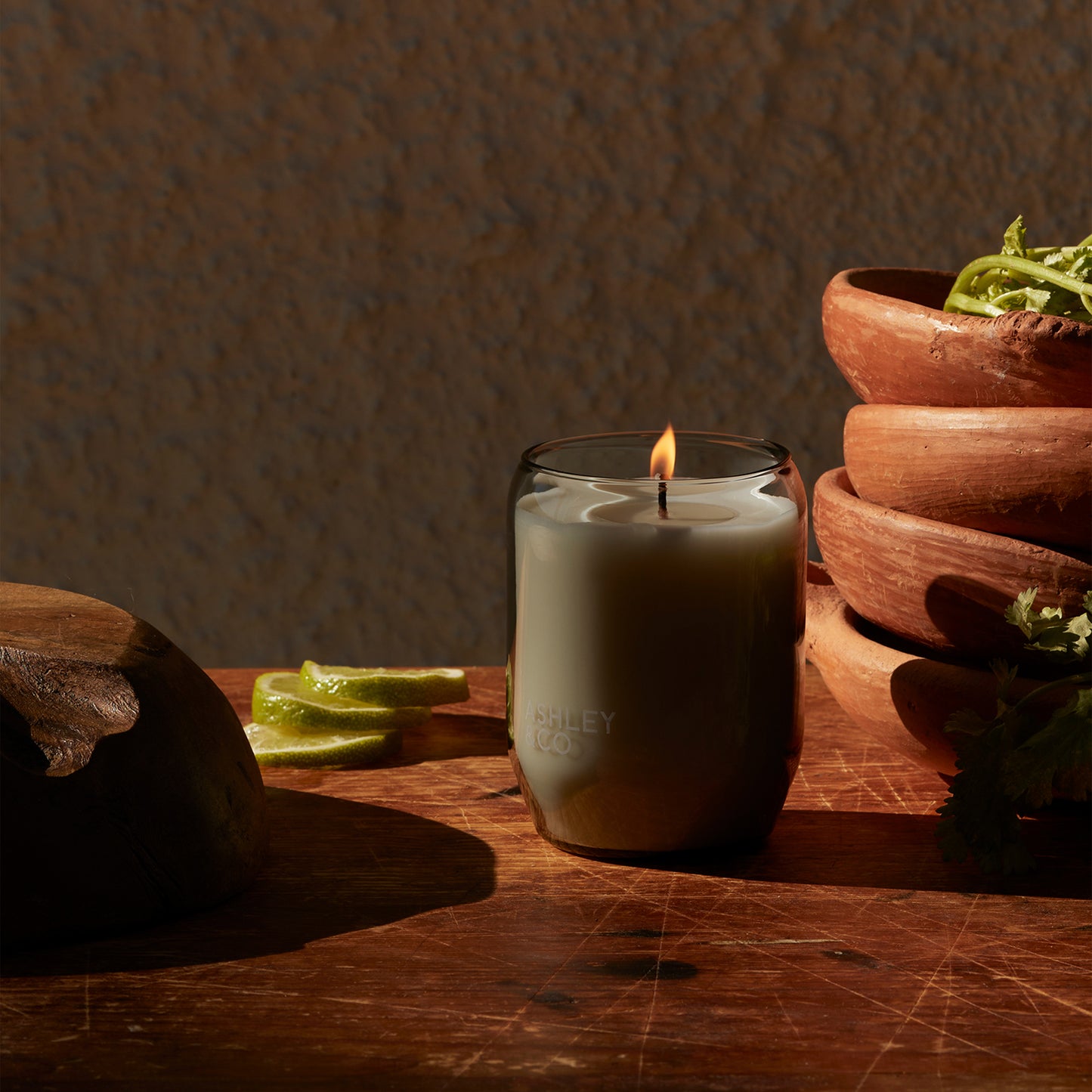 Ashley and Co 'Waxed Perfume' scented candle in lotus leaf and lustre fragrance on a counter with salad bowls in background.