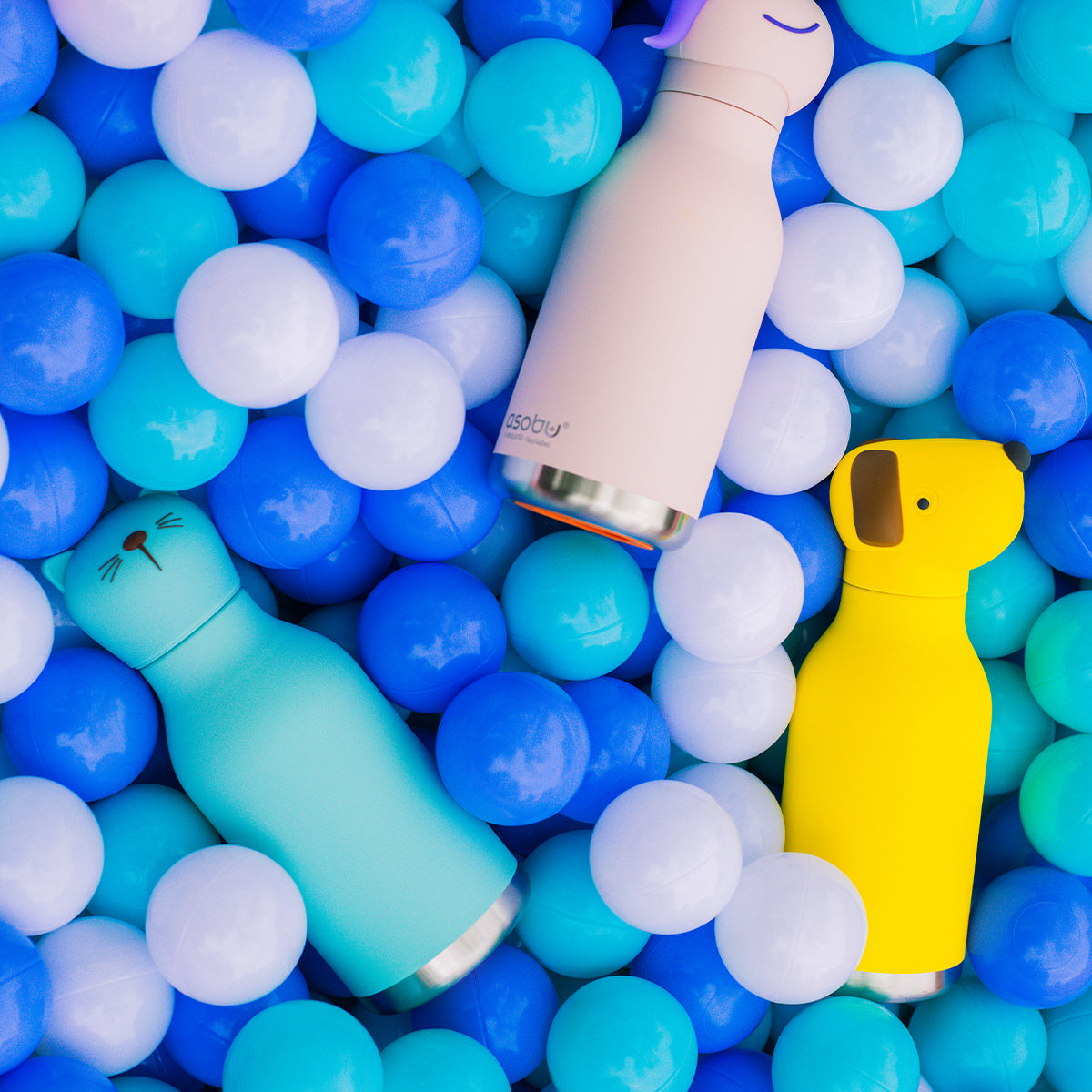 Cat, dog and rabbit Bestie Bottles by Asobu placed in a ball pit.