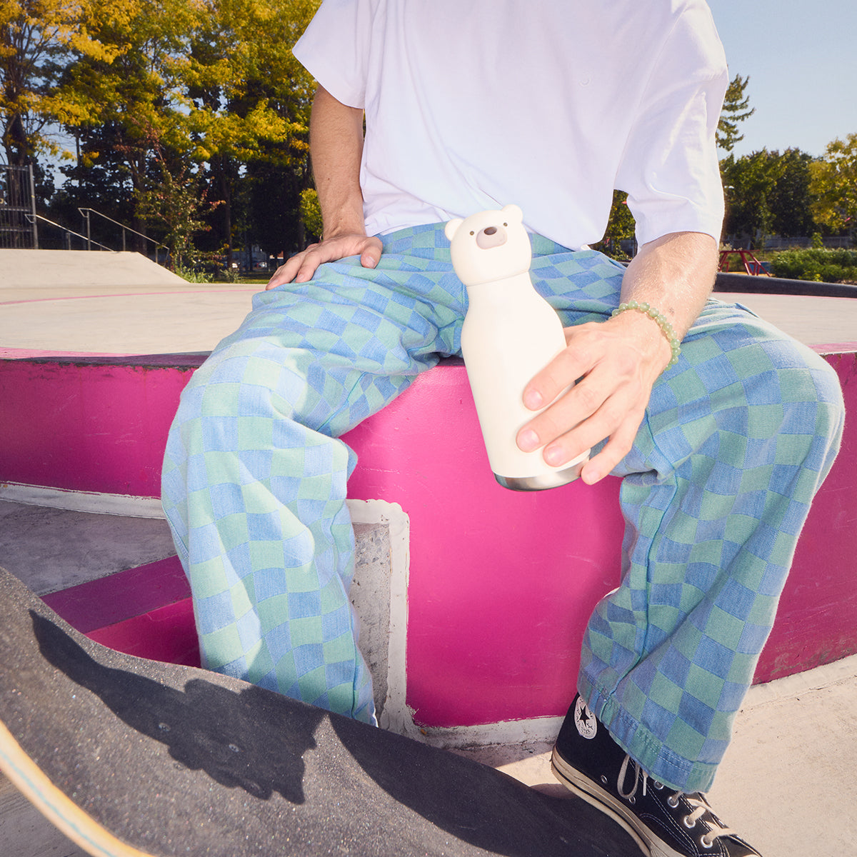 A Polar Bestie Bottle by Asobu being held by a person in a skate park.