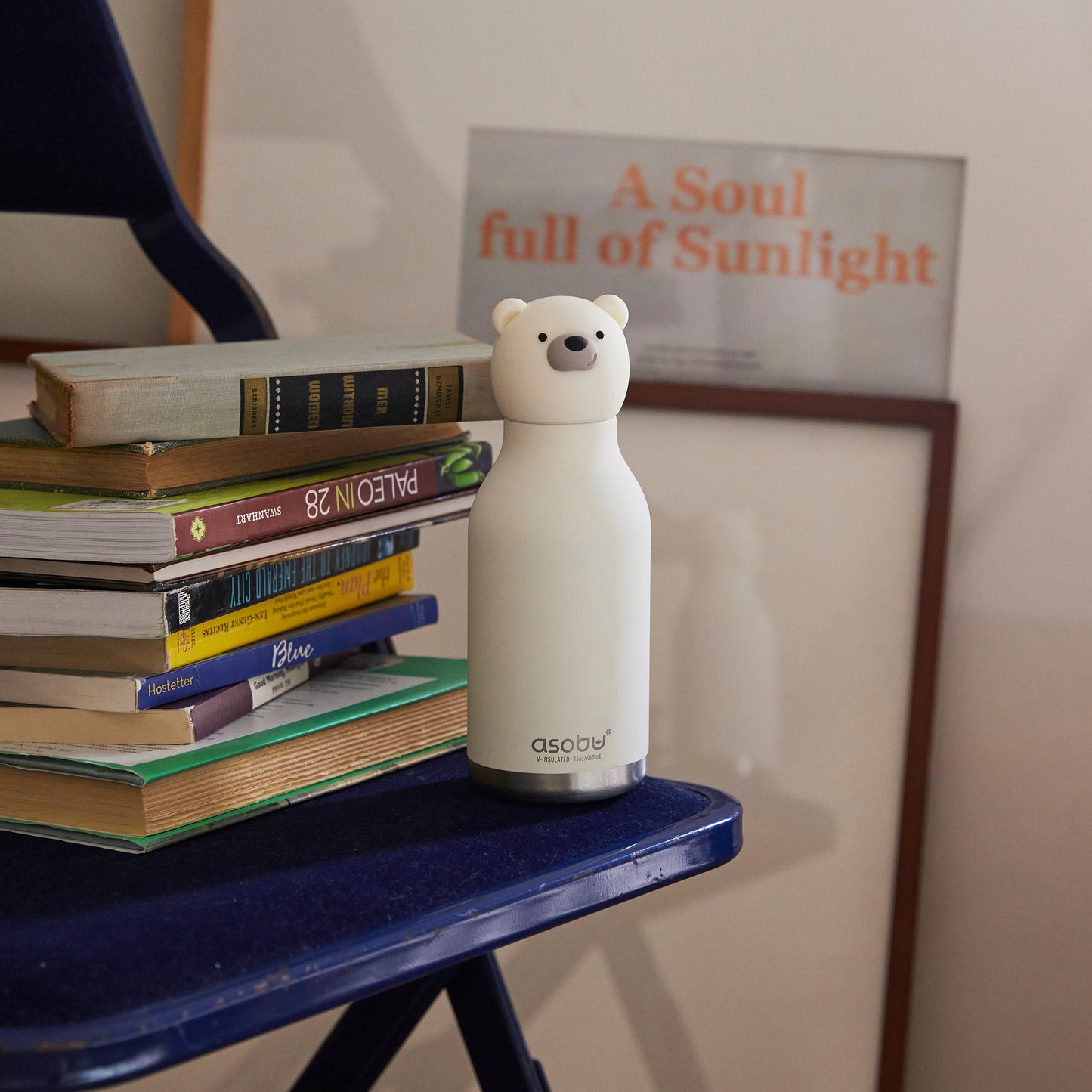 A Polar Bestie Bottle by Asobu sitting next to a pile of books,