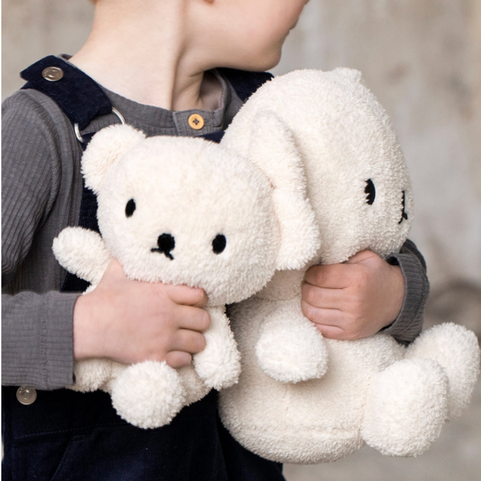 Young boy holding assorted sizes of Bon Ton Toys cream terry Borris bear in his arms lifestyle shot