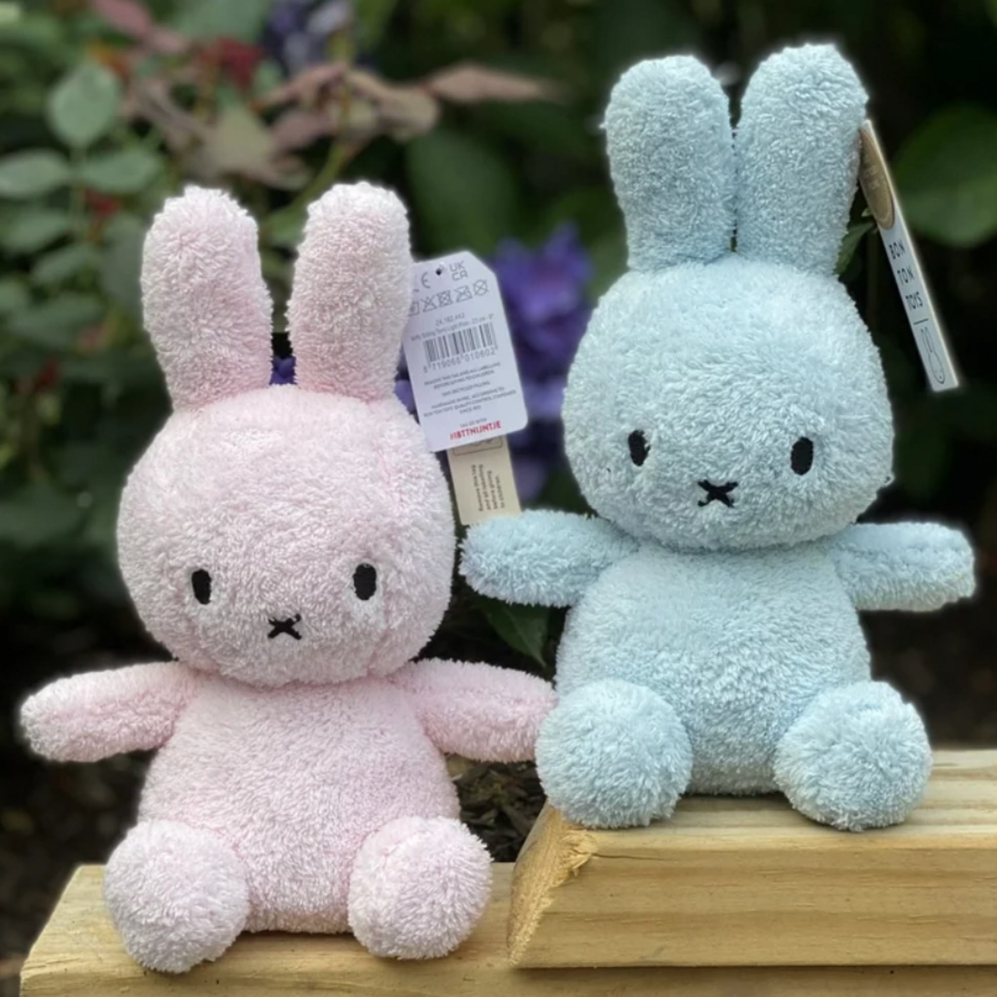 Two light blue and pink Bon Ton Toys Sitting Miffys outside in garden sitting staggered next to eachother lifedtyle shot