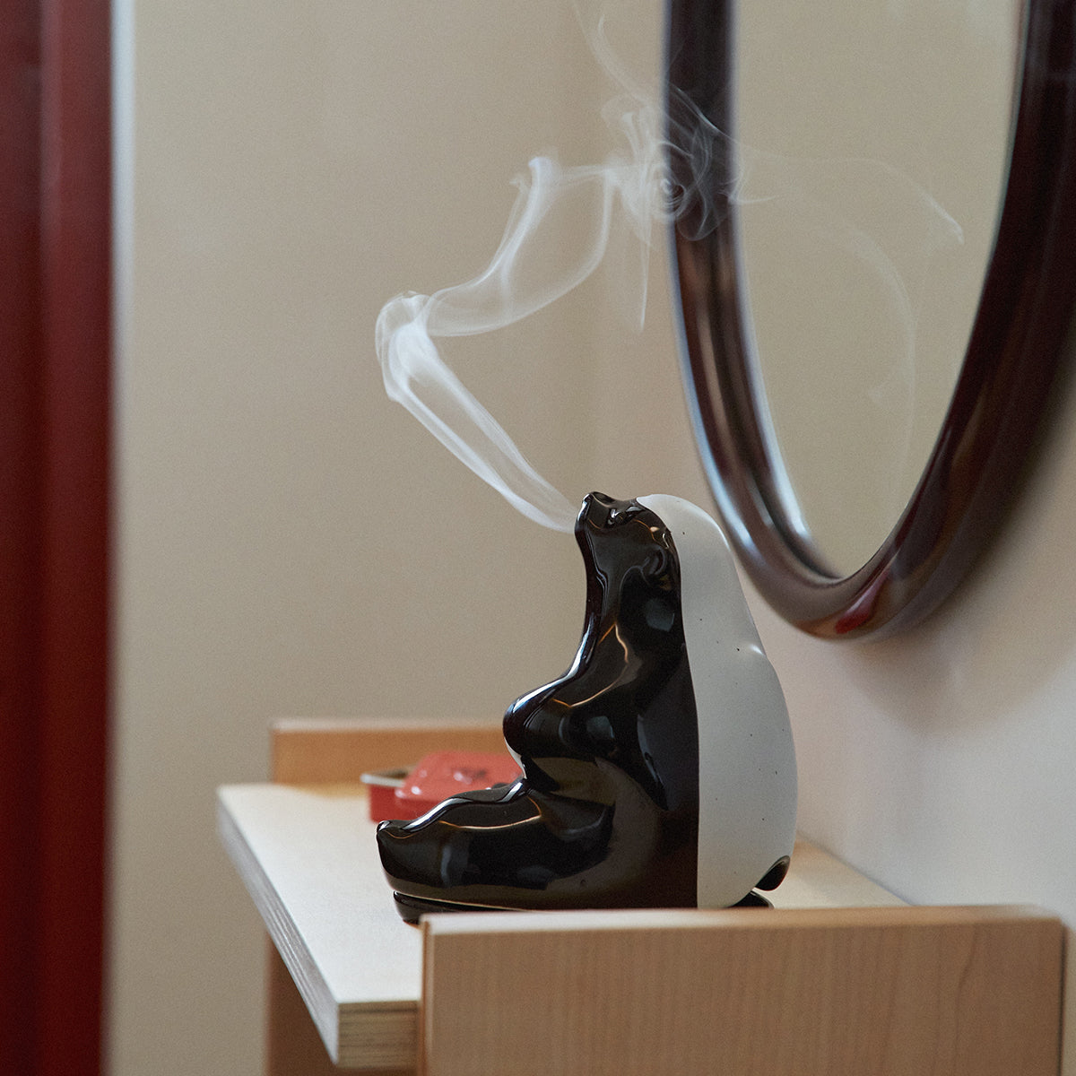 Collins ceramic smoking honey badger incense holder on wooden shelf in front of red curtain