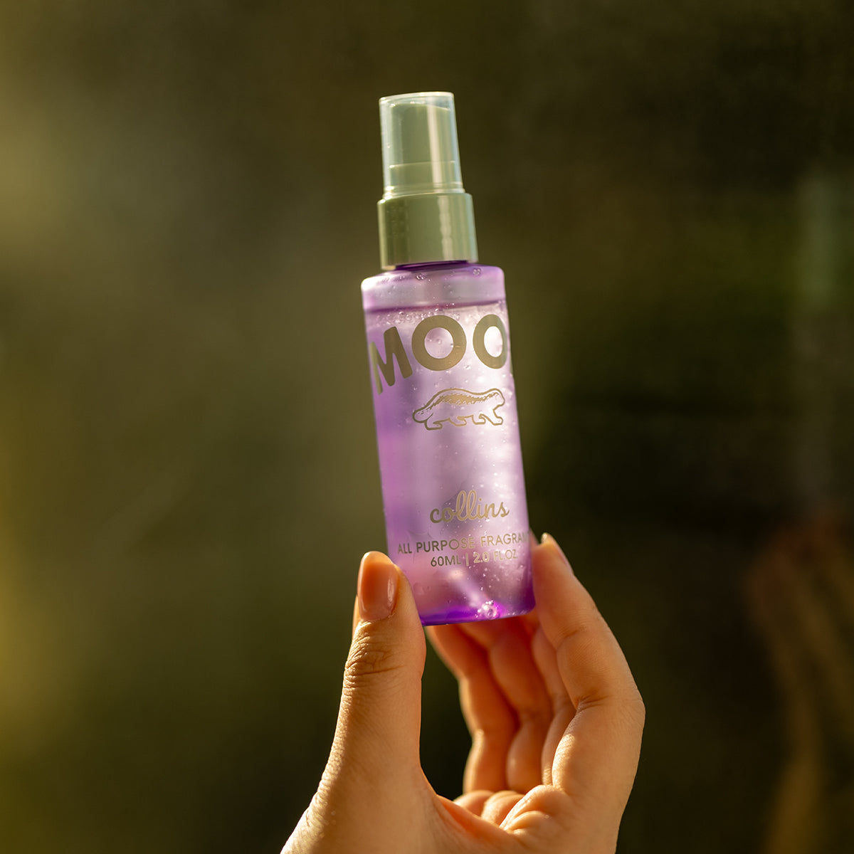 Close up shot of a woman holding a travel sized bottle of french violet scented mood water by collins.