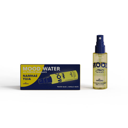 A travel sized bottle of yuzu scented mood water by collins, placed next to its box.
