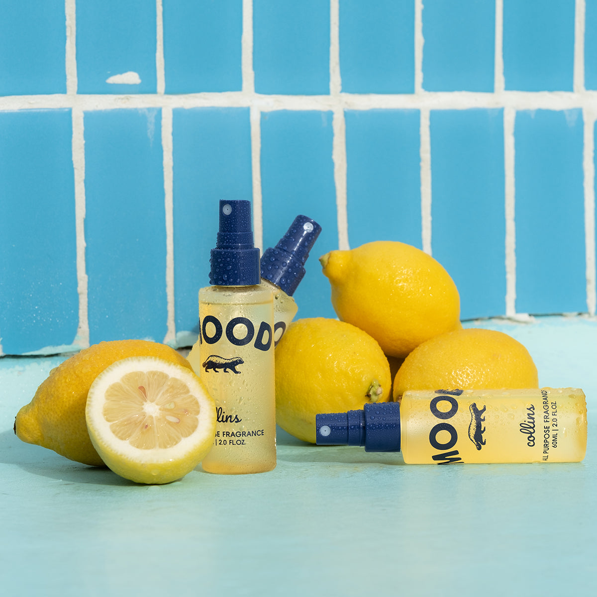 3 travel sized bottle of yuzu scented mood water by collins, with a pile of yuzu fruit in a blue environment.