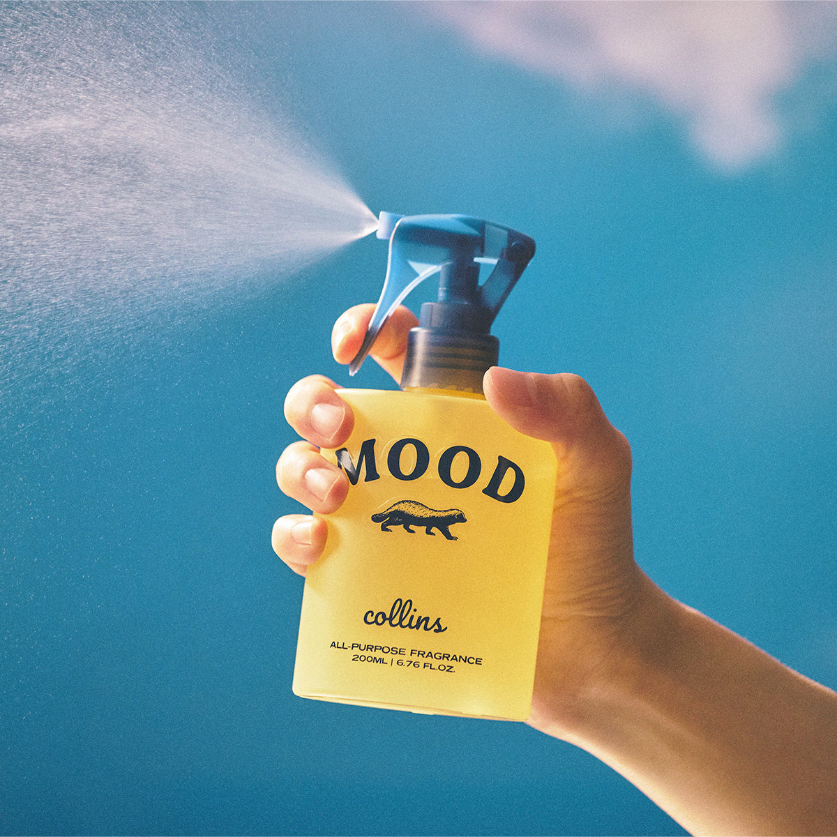 Collins Yuja 200ml water based Mood Water being sprayed with a blue background 