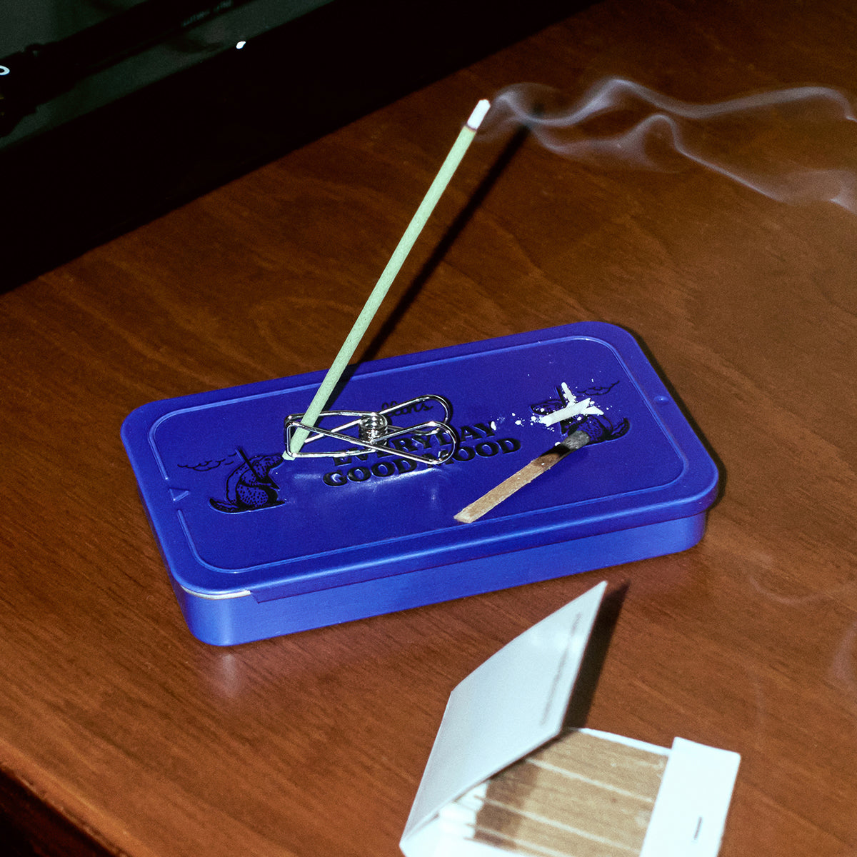Collins ''Splash Diving' natural incense burning on the metal tin on a wooden table