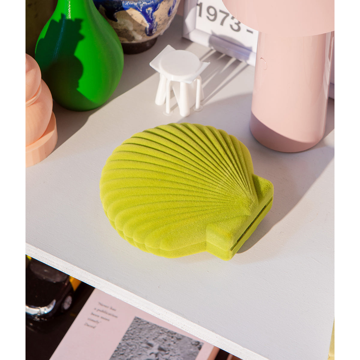 Closed DOIY light green velvet venus jewelry box on white table next to blush lamp and green vase