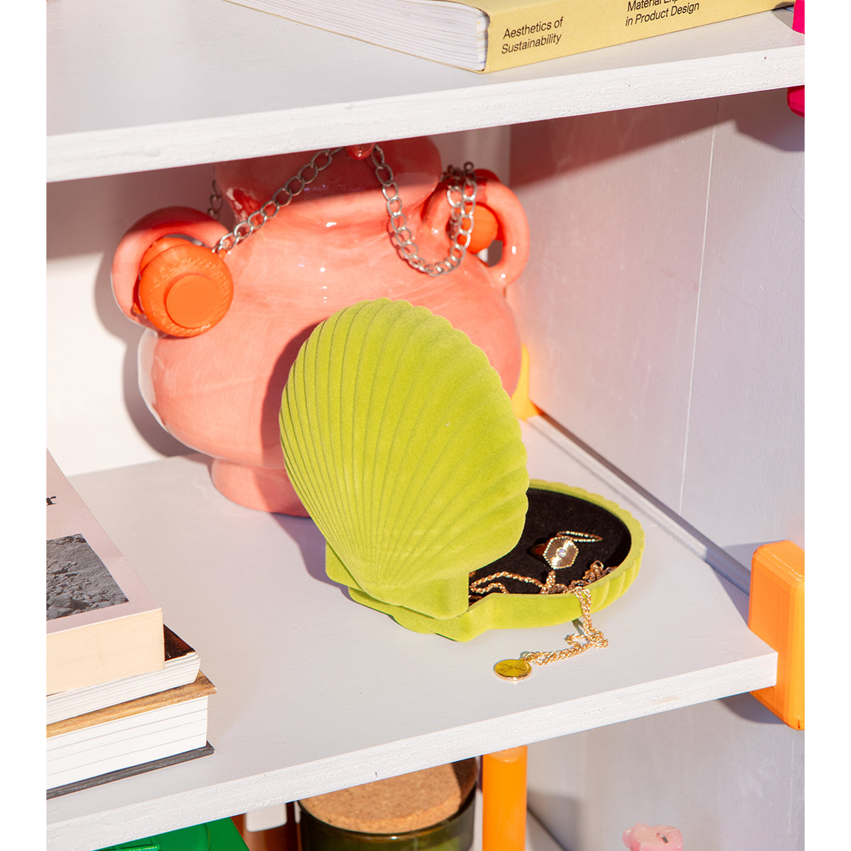 Open DOIY light green velvet venus jewelry box with jewels spilling out onto white shelf in front of apricot coloured pot