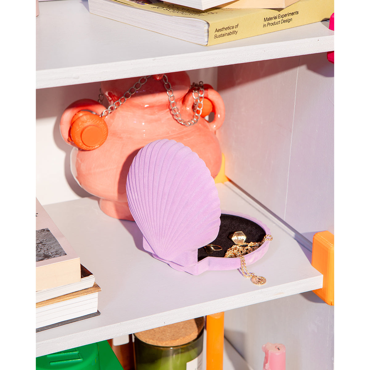 Open DOIY lilac velvet venus jewelry box with jewels spilling out onto white shelf in front of apricot coloured pot