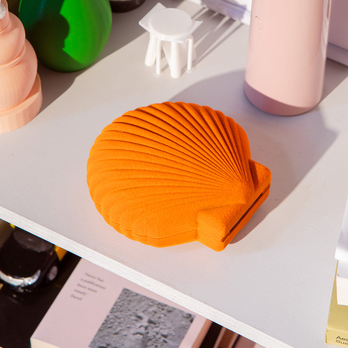 Closed DOIY orangevelvet venus jewelry box on white table next to blush lamp and green vase
