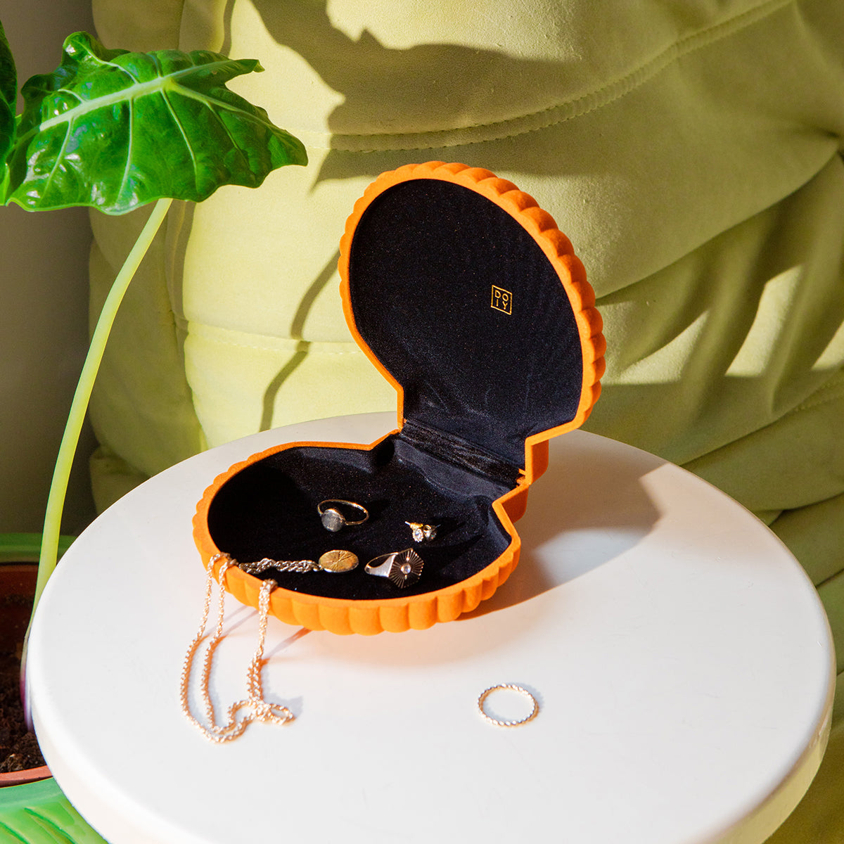 Open DOIY orange velvet venus jewelry box filled with jewels on white round side table 