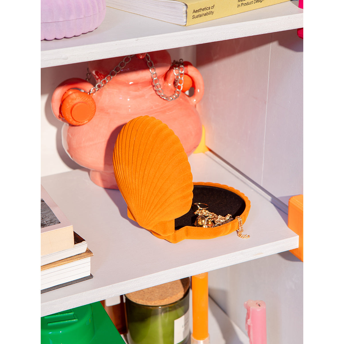 Open DOIY orange velvet venus jewelry box with jewels spilling out onto white shelf in front of apricot coloured pot