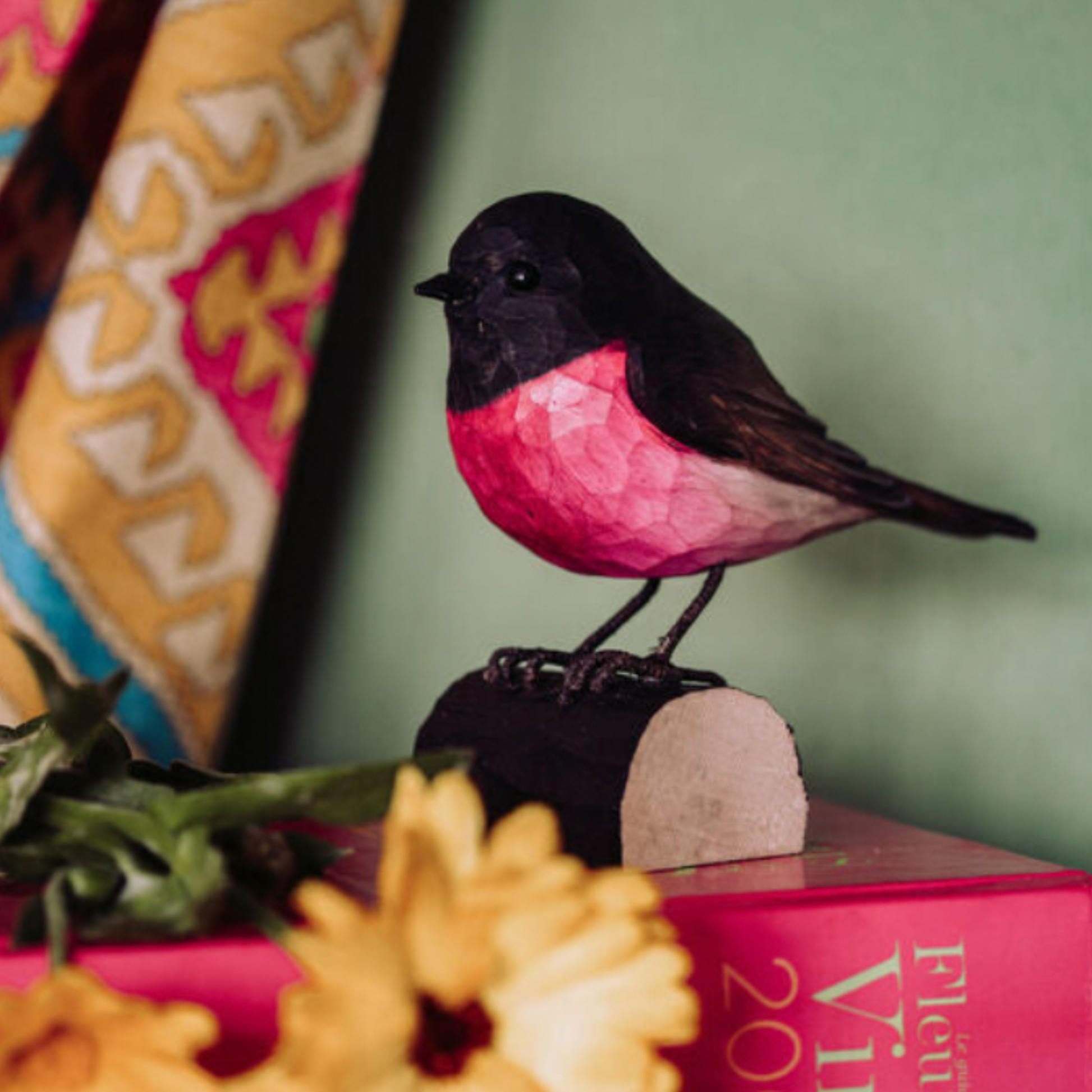 Close up of Wildlife Garden Deco Bird Small Pink Robin on display on stack of books
