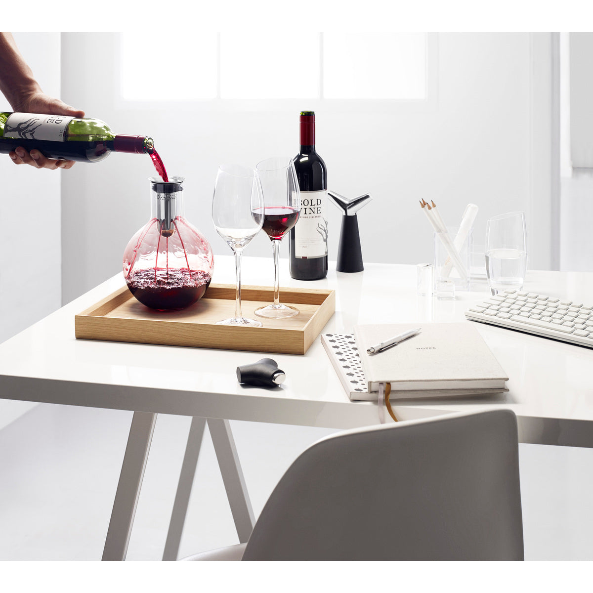 Bulb shaped Decanter Carafe by Eva Solo resting ona serving tray as wine is deanted into it on a desk setting
