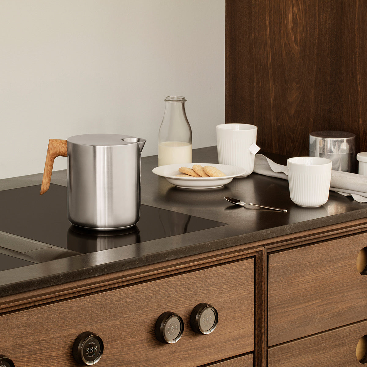 Shown on the electric stove Eva Solo Nordic Kitchen induction kettle - black and silver stovetop kettle with oak handle, stainless steel and aluminum body, 1L capacity for fast boiling on induction.