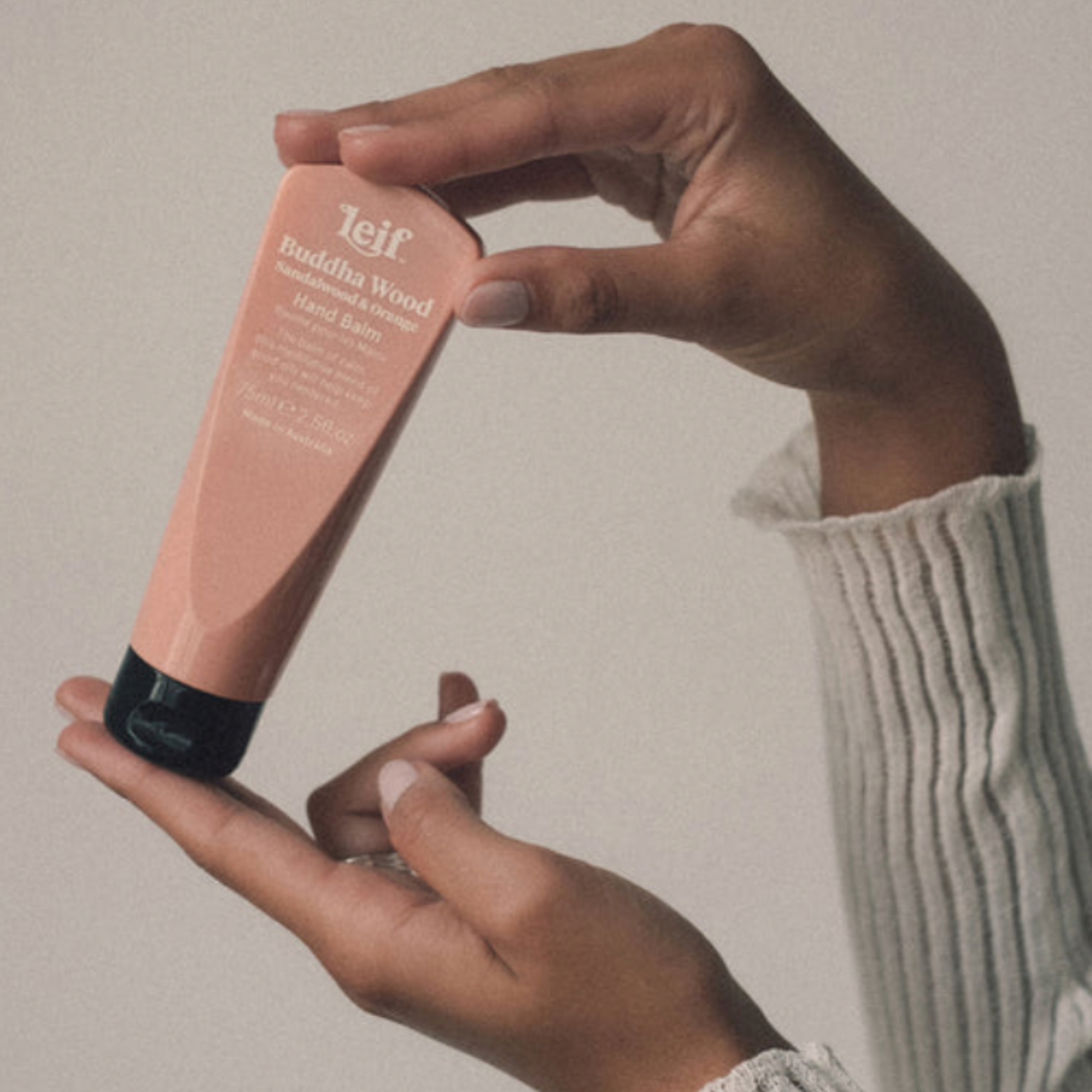 Womans hand holding a bottle of Leif hand balm 100 ml Buddah Wood