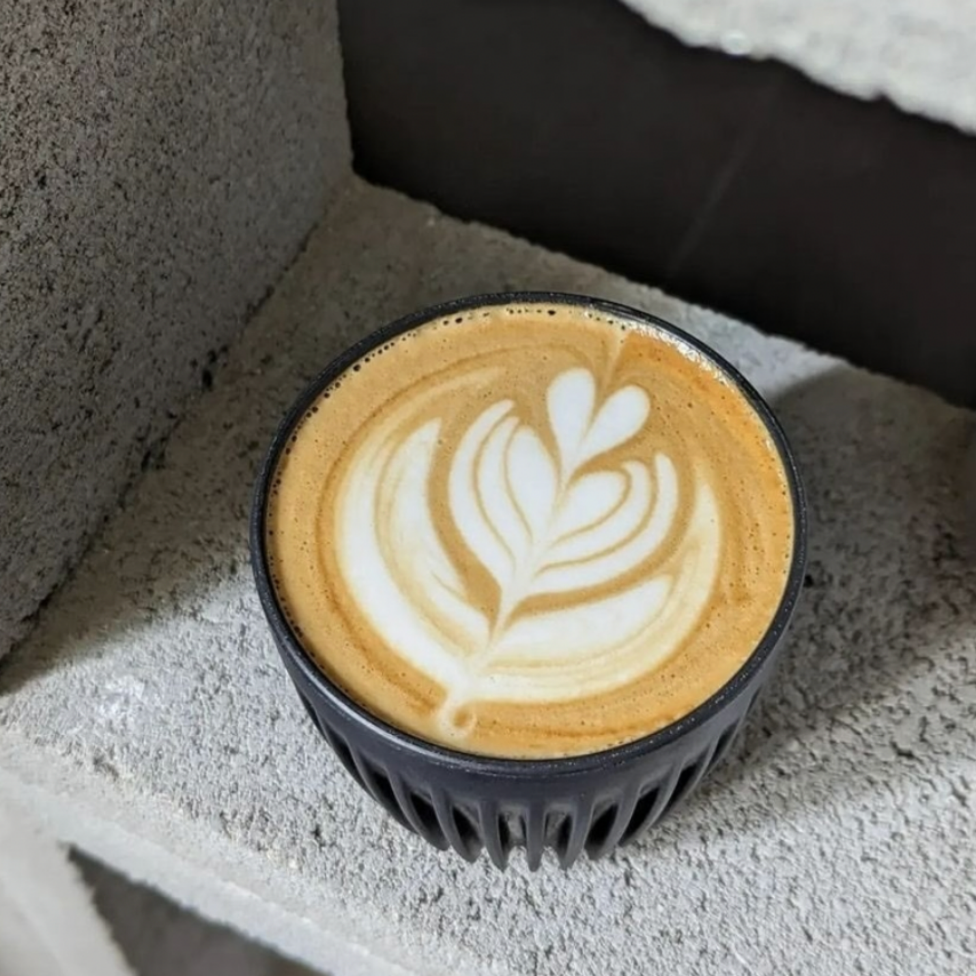 HuskeeCup 6oz with Lid Charcoal out of on display on cinder blocks with coffee in the cup 