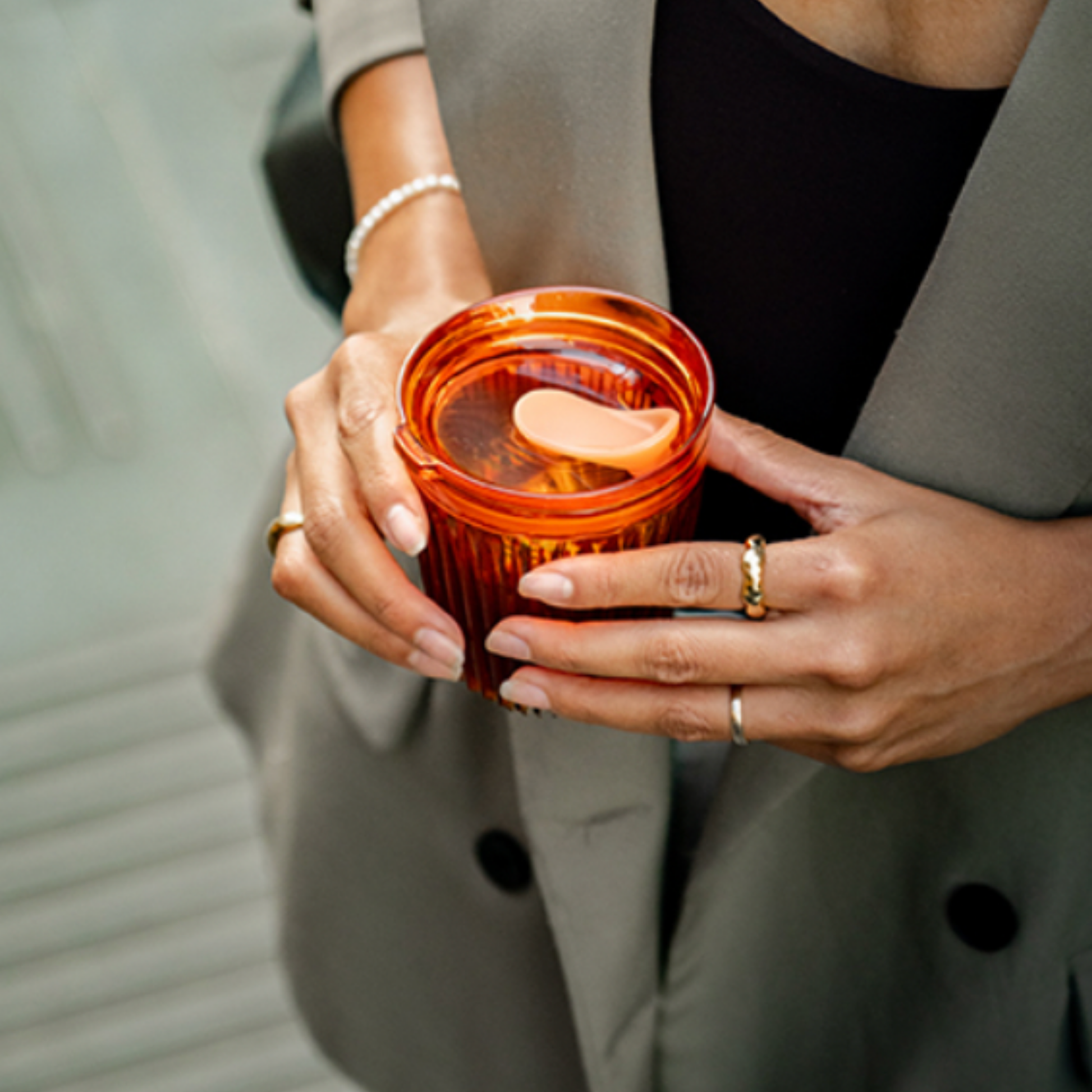 Woman in suit holding HuskeeRenew Cup 8oz with Lid Amber