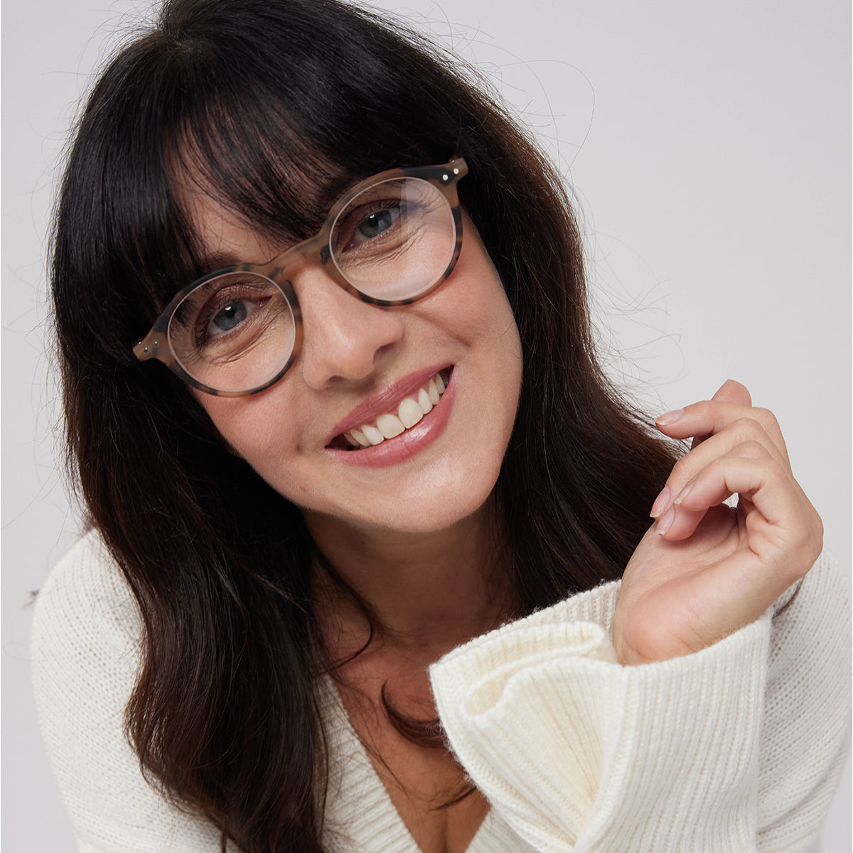 Woman in cream jumper wearing Izipizi shape d light tortoise reading glasses