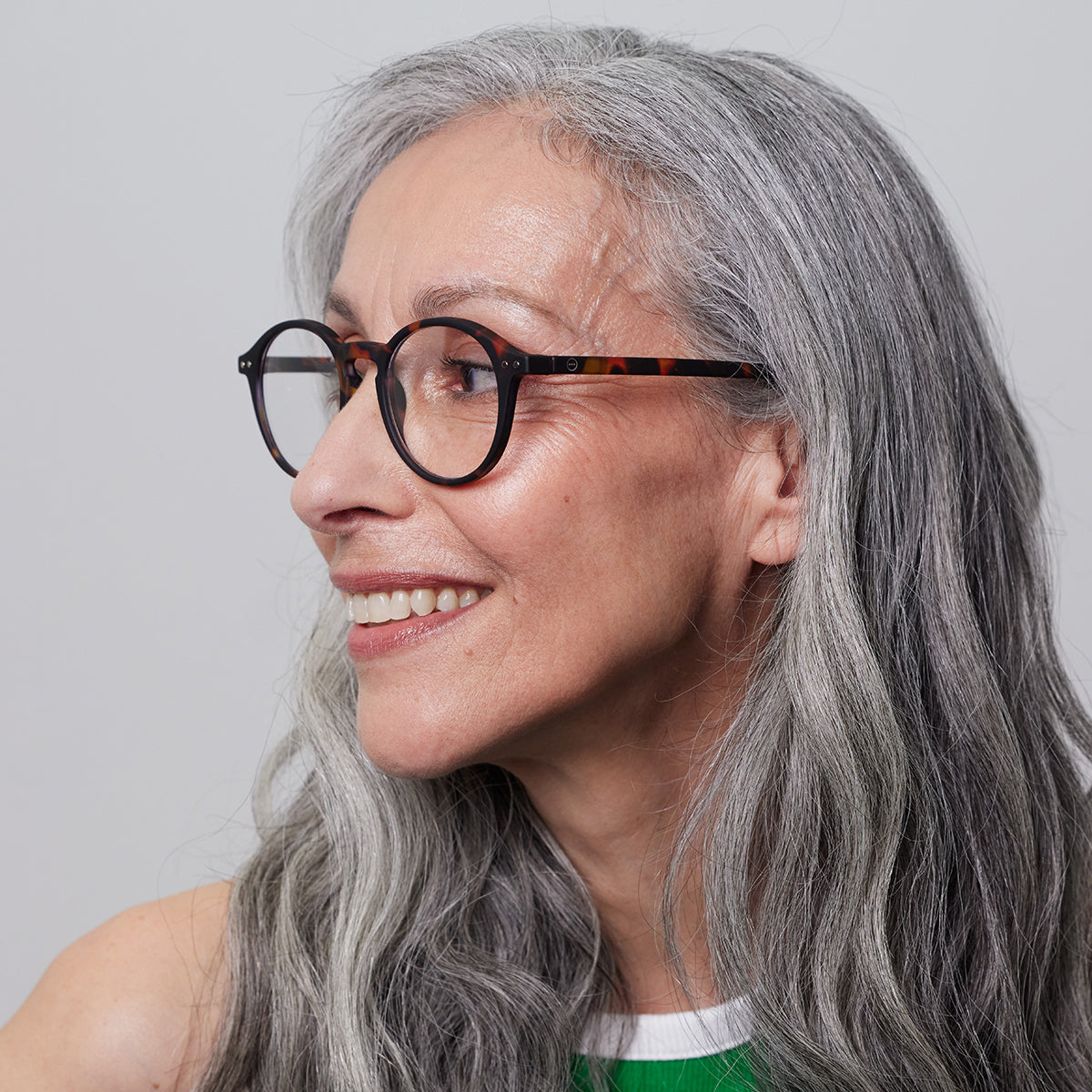 Woman in cream jumper wearing Izipizi shape d light tortoise reading glasses