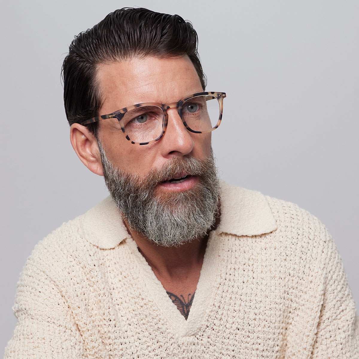 Man in cream jumper wearing Izipizi shape e light tortoise reading glasses