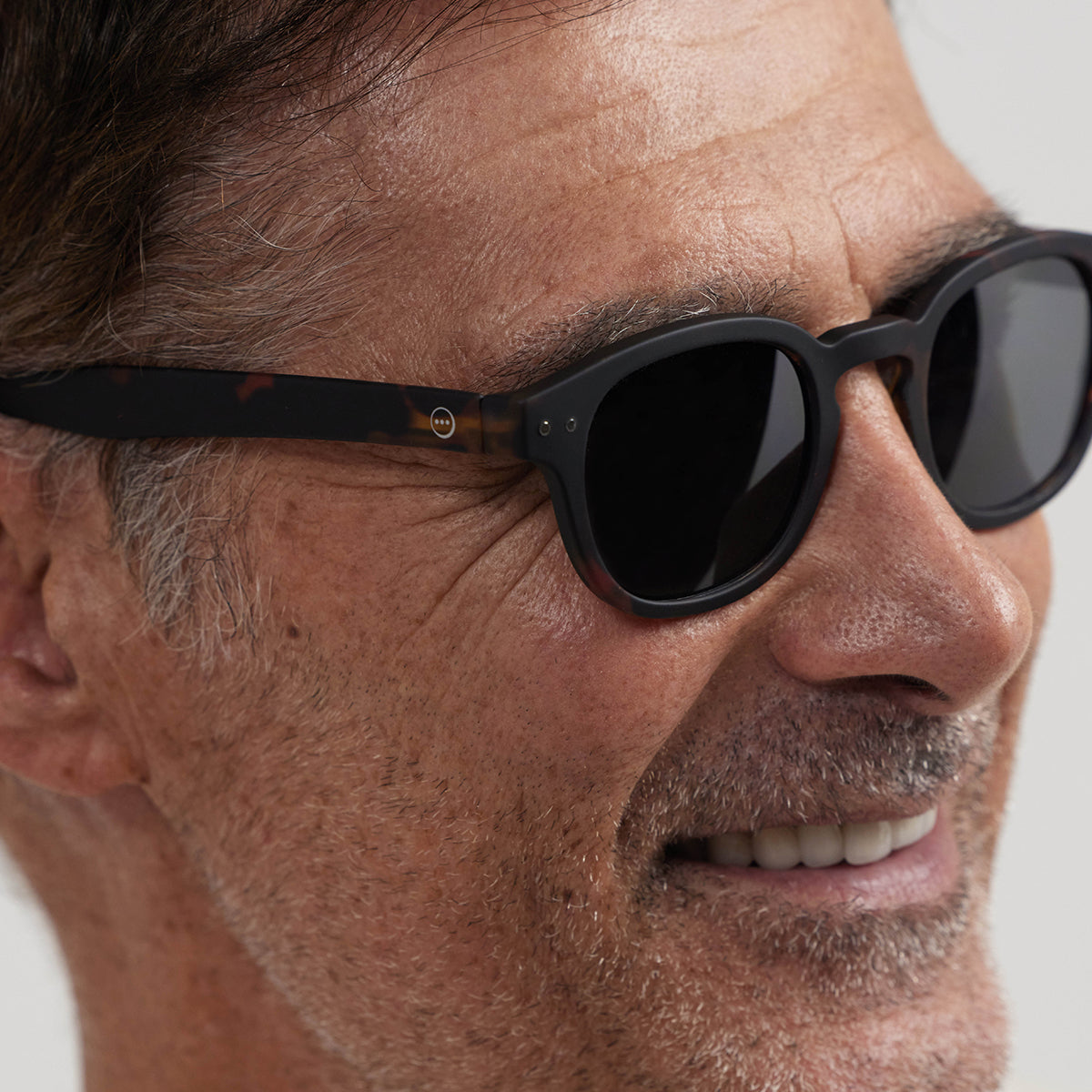 Close up of man wearing Izipizi shape c tortoise sunglasses on an angle