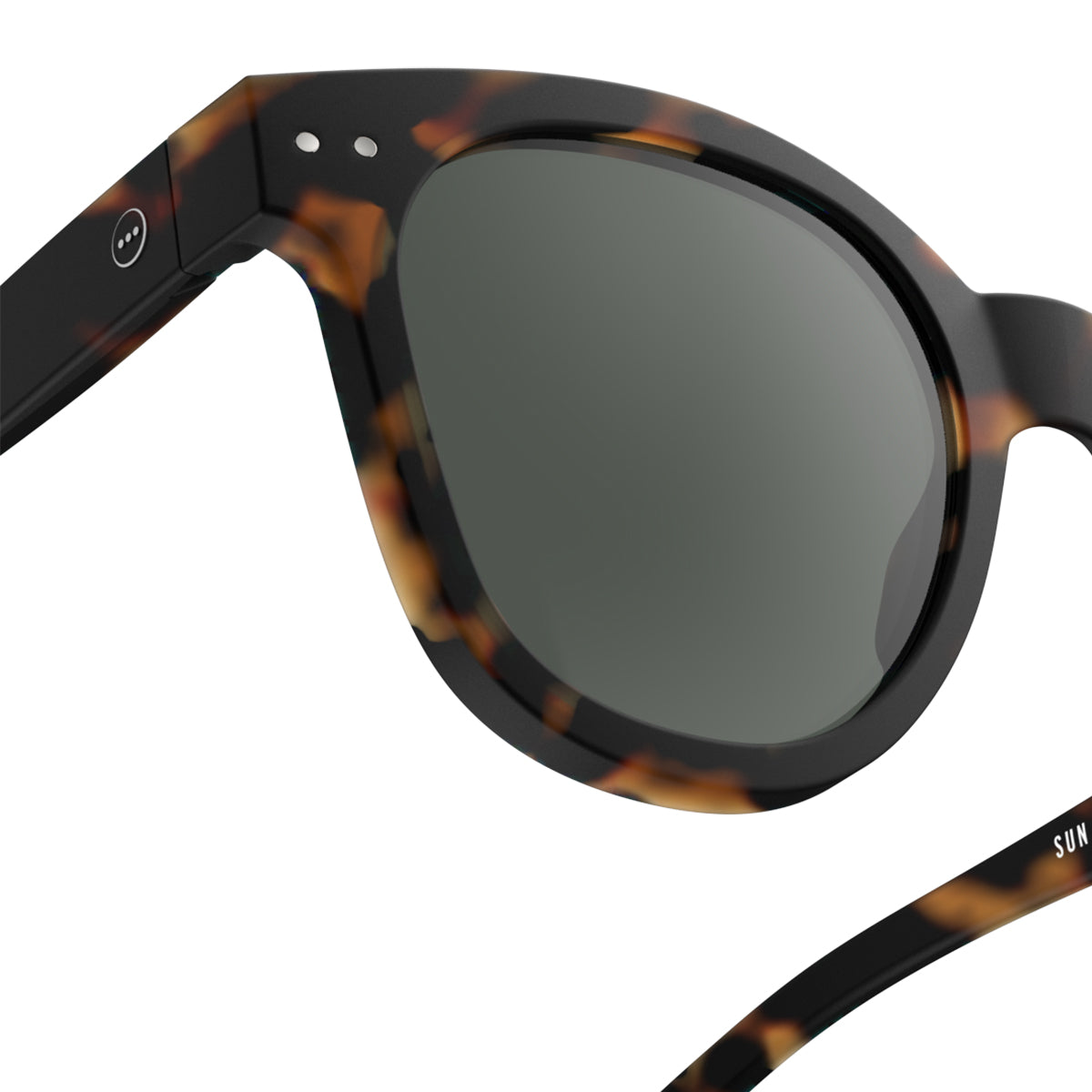 Woman with brown curly hair wearing Izipizi shape n tortoise sunglasses in front of lattice wall