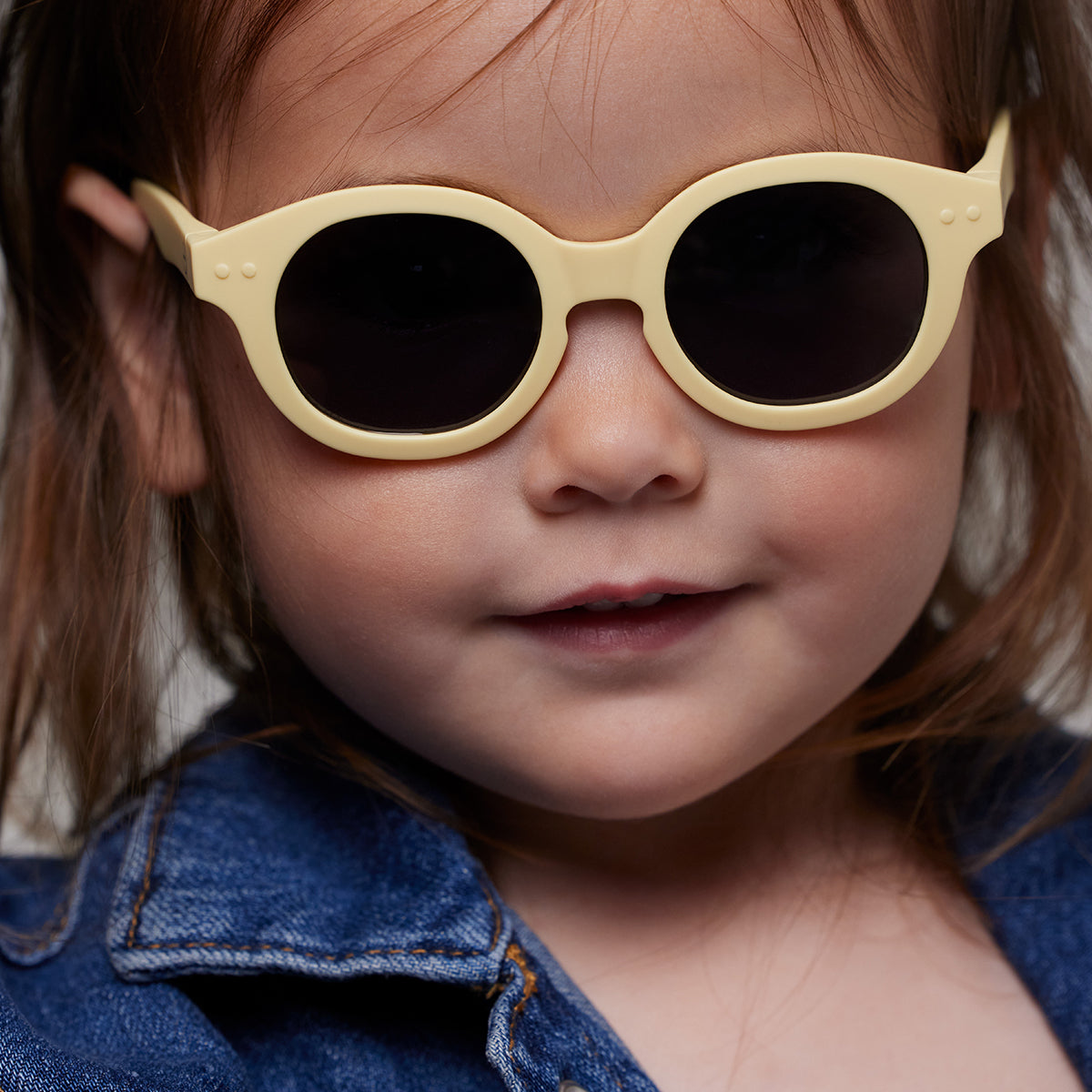 Little girl in denim jacket wearing Izipizi kids sunglasses shape c lemonade