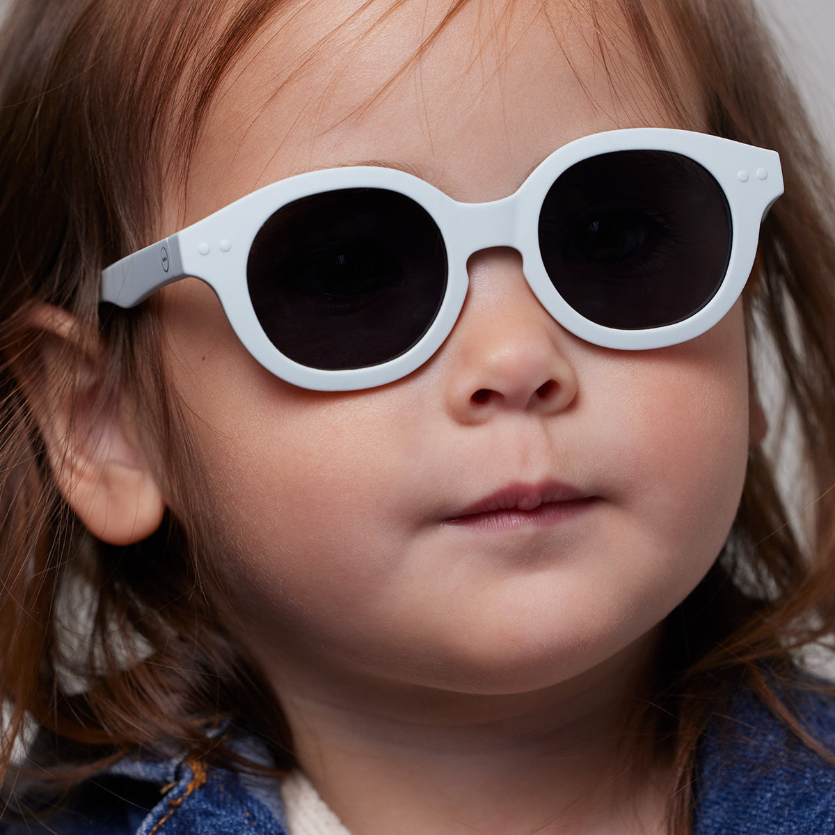 Little girl in denim jacket wearing Izipizi kids sunglasses shape c sweet blue