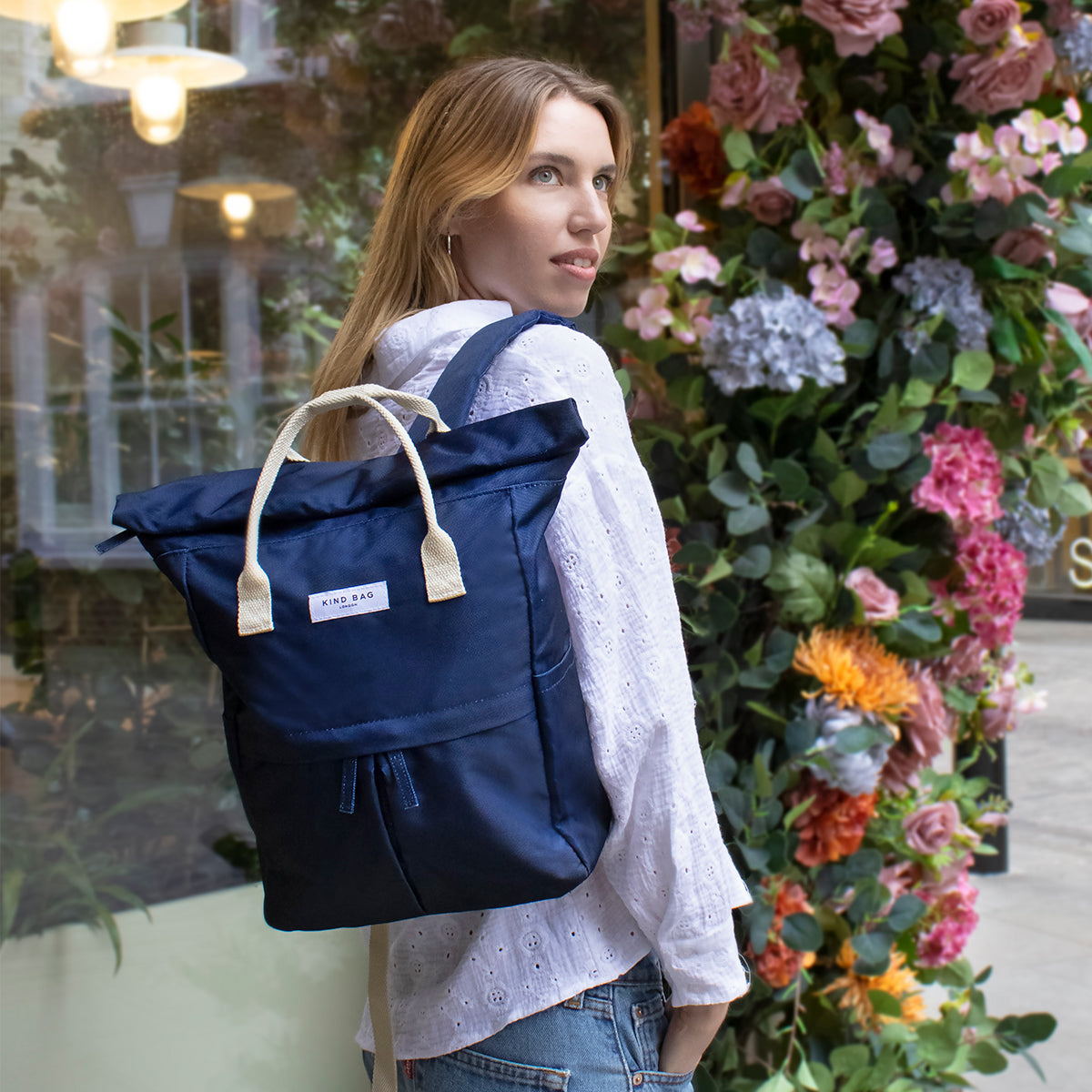 Kind Bag's Backpack Medium in colour navy shown slung over a woman's shoulder.